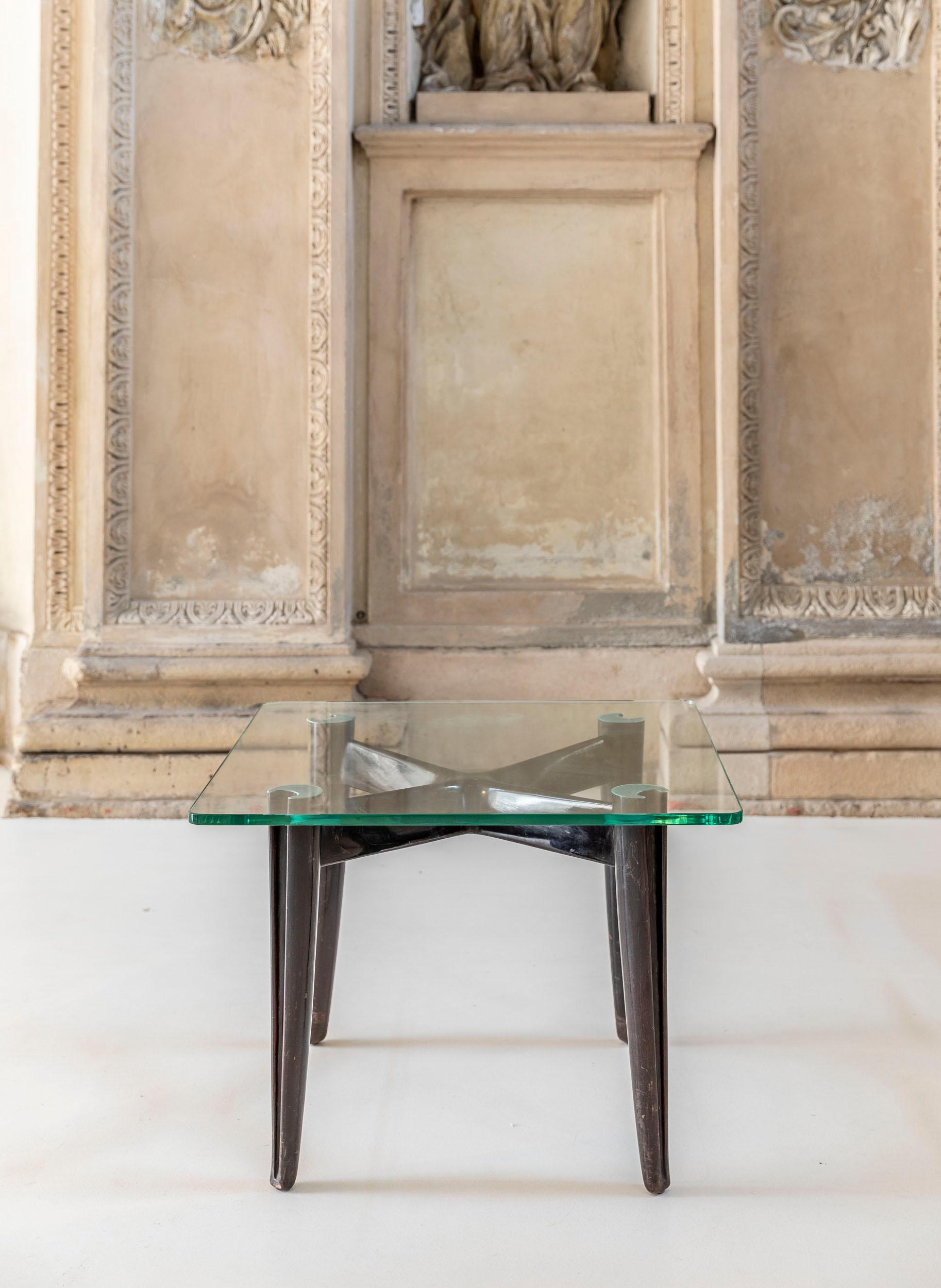 
Die Holzstruktur mit vier Beinen hat die ikonische spitz zulaufende Form mit gekreuztem Design von Osvaldo Borsani. Die ursprüngliche Platte ist ein dickes Klarglas in ausgezeichnetem Zustand.
 