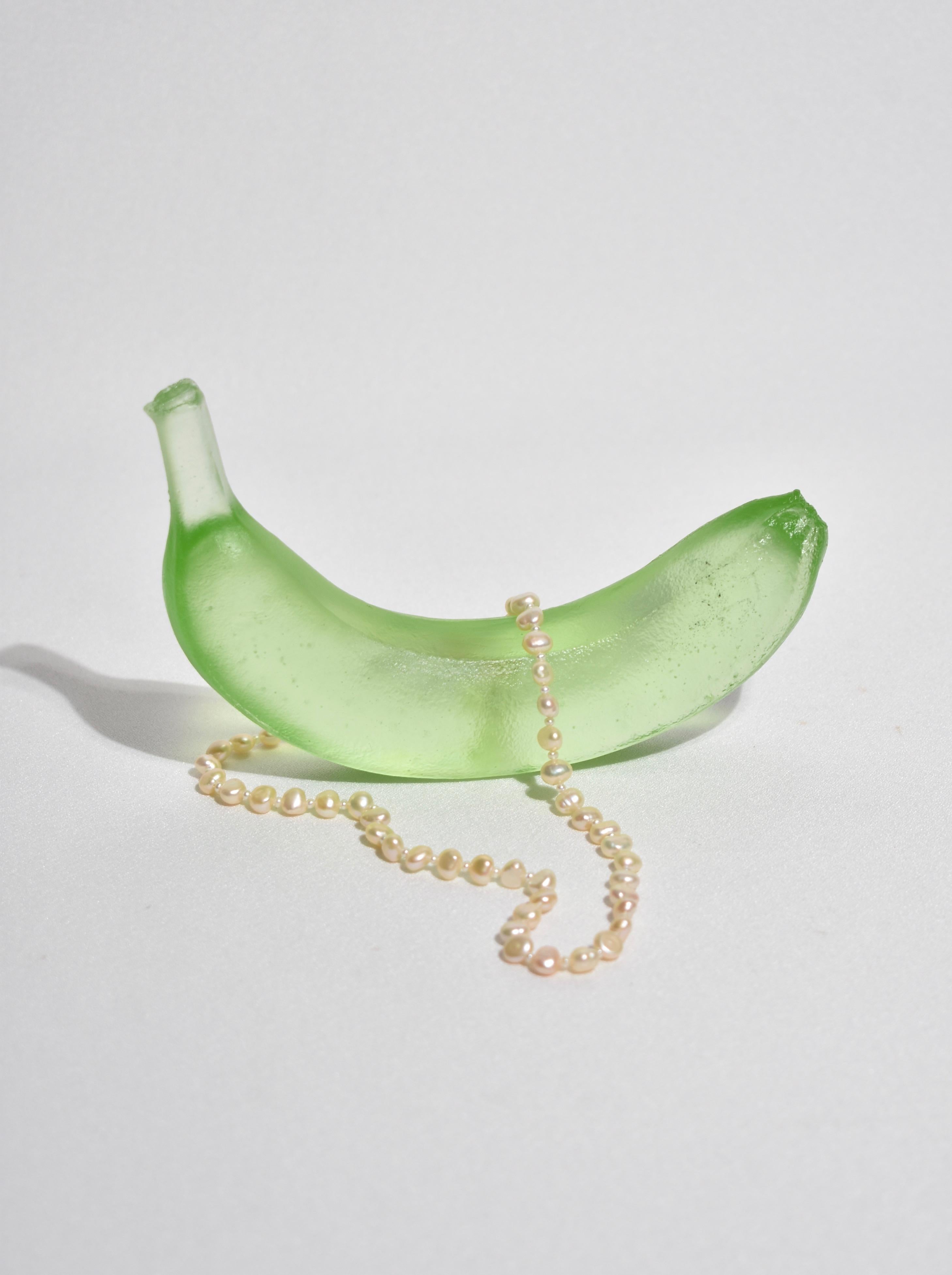Casted glass banana in lime by Devon Made inspired by blown glass fruit makers and collectors from the 1960's. The light playful approach to everyday fruit is contrasted with the heaviness of the crystal glass, a unique material that catches and