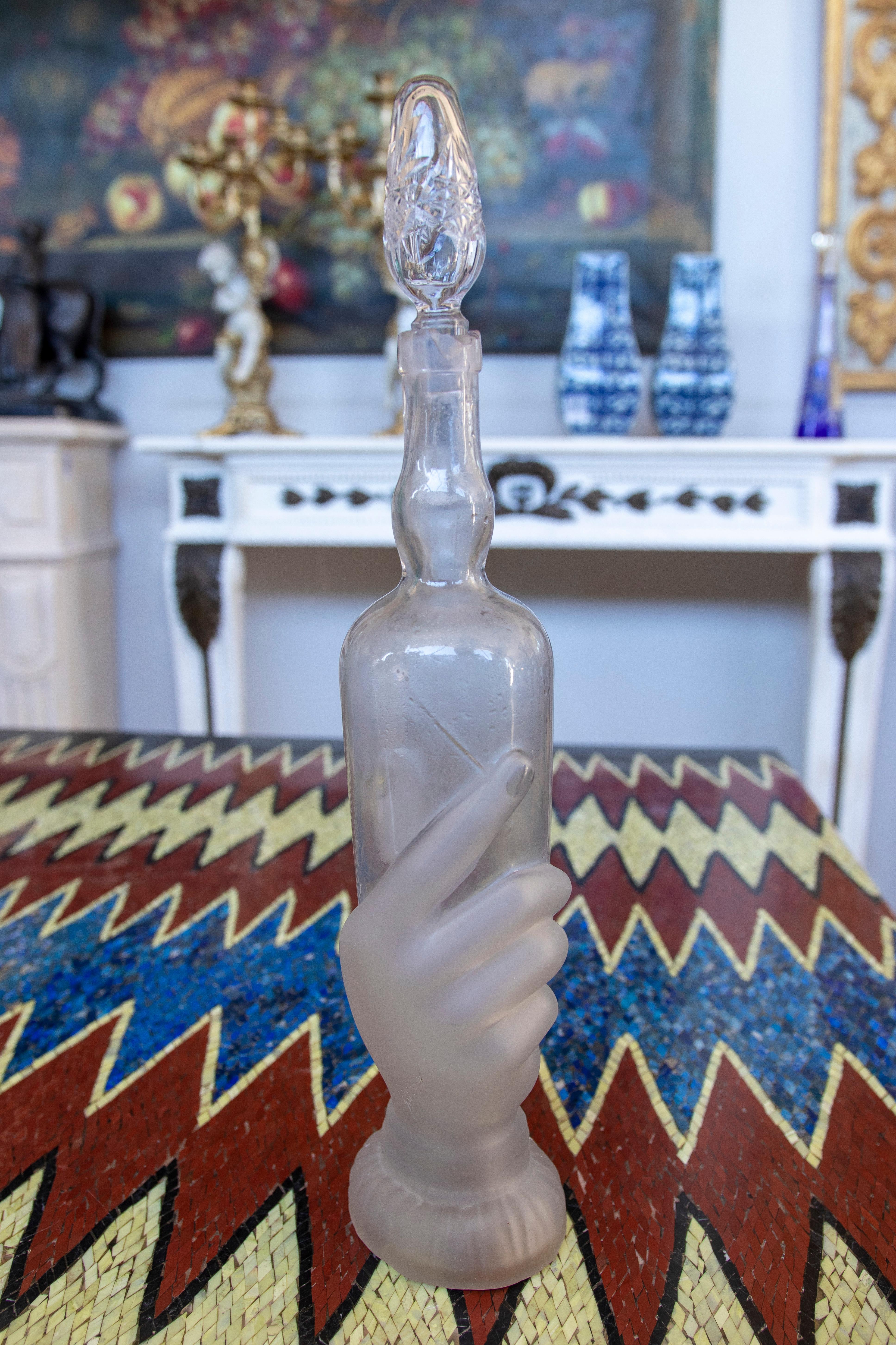 Glass bottle with hand-shaped base and translucent and normal finishes.