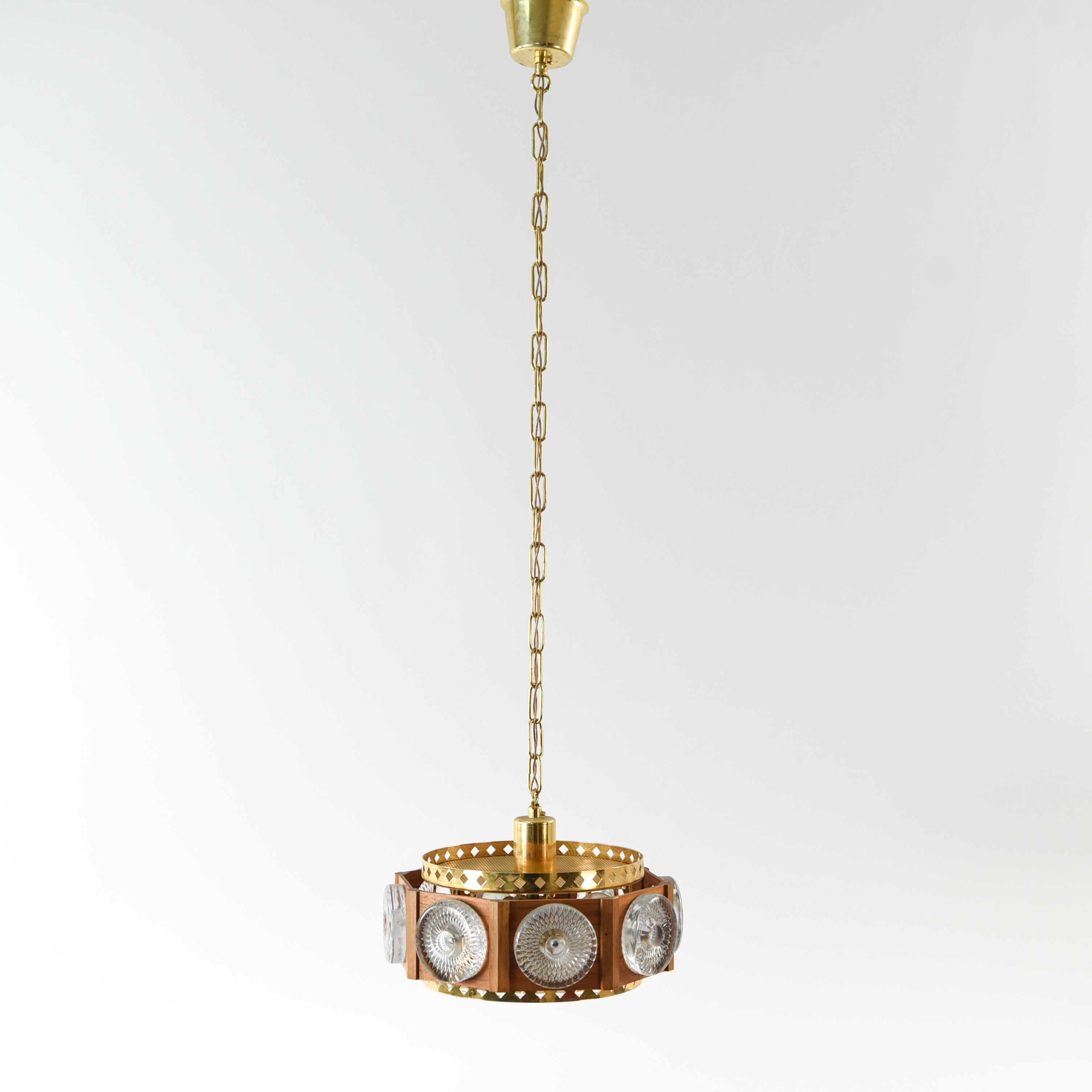 This is a beautiful Swedish midcentury pendant chandelier designed by Carl Fagerlund for Orrefors. This piece is unusual as it incorporates a teak wood frame, unlike most of Fagerlund's designs which are solely brass and glass, and features textured