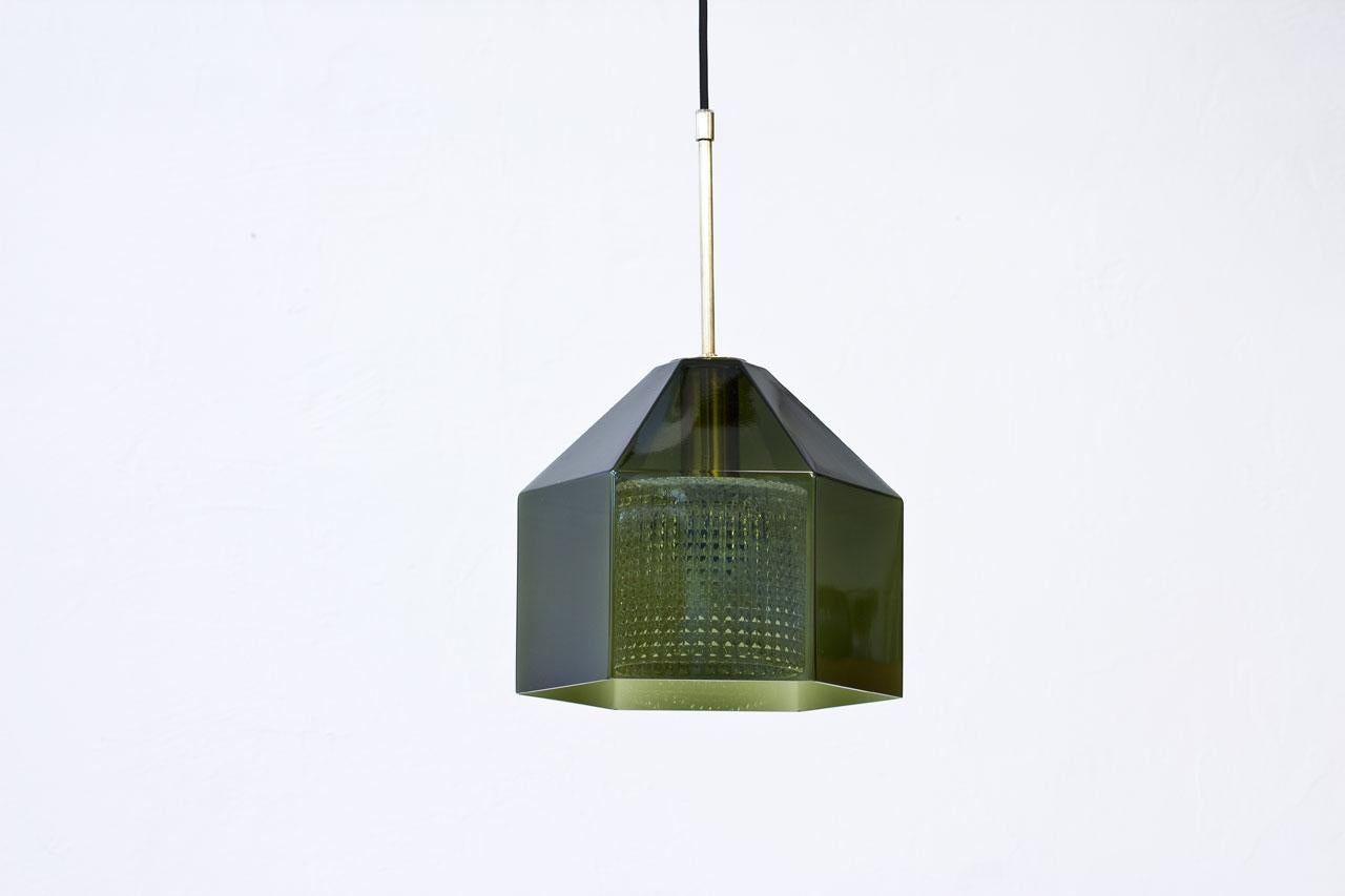 Pendant lamp designed by Carl Fagerlund for Swedish glass maker Orrefors during the 1960s. 
Hexagon shaped outer cup of green tinted glass with internal diffuser in clear pressed glass. 
Brass fittings with new electricity.