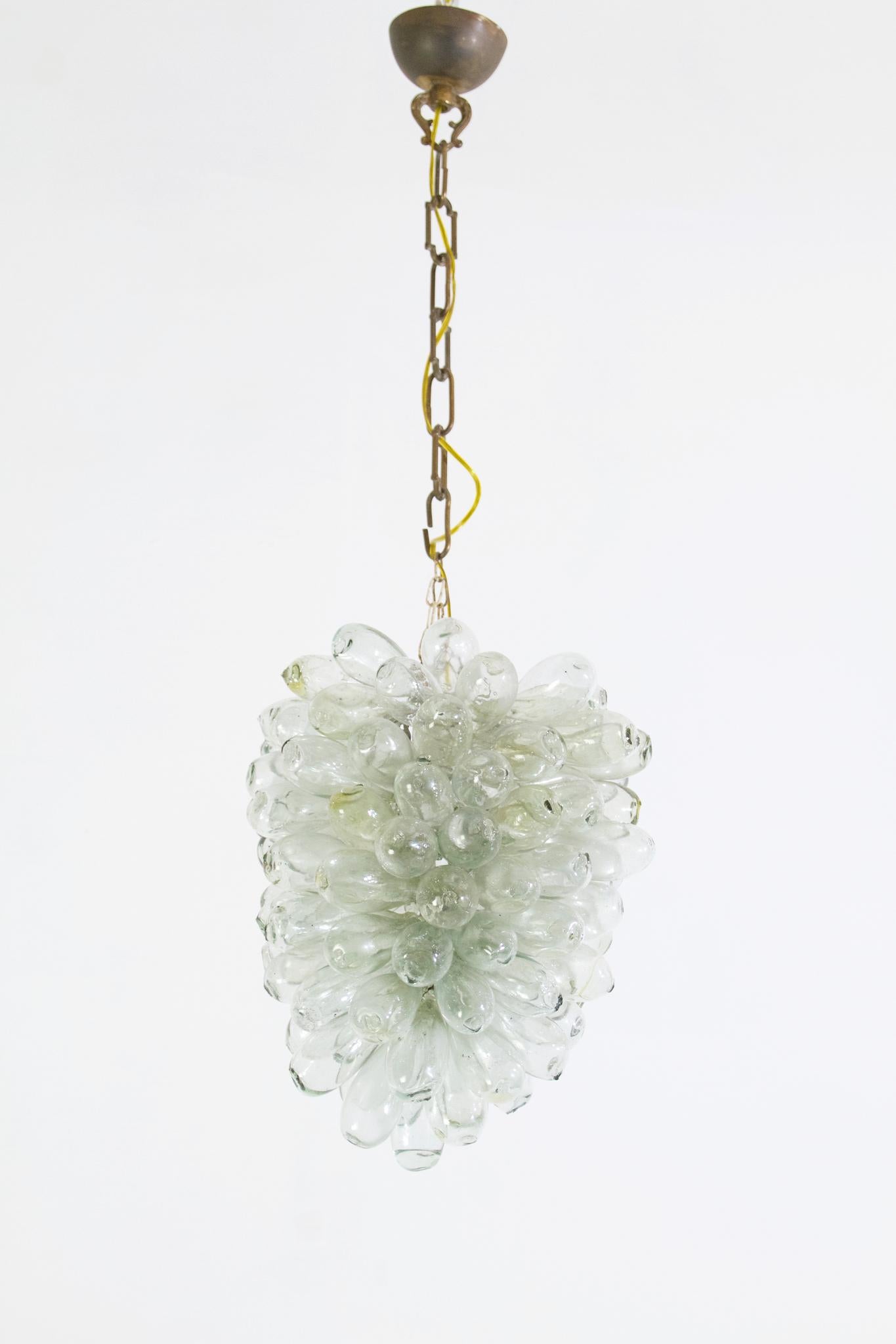 This ceiling lamp is completely handmade by making small bubbles out of recycled glass which are assembled into a grape like shape. No cracks or breakages.