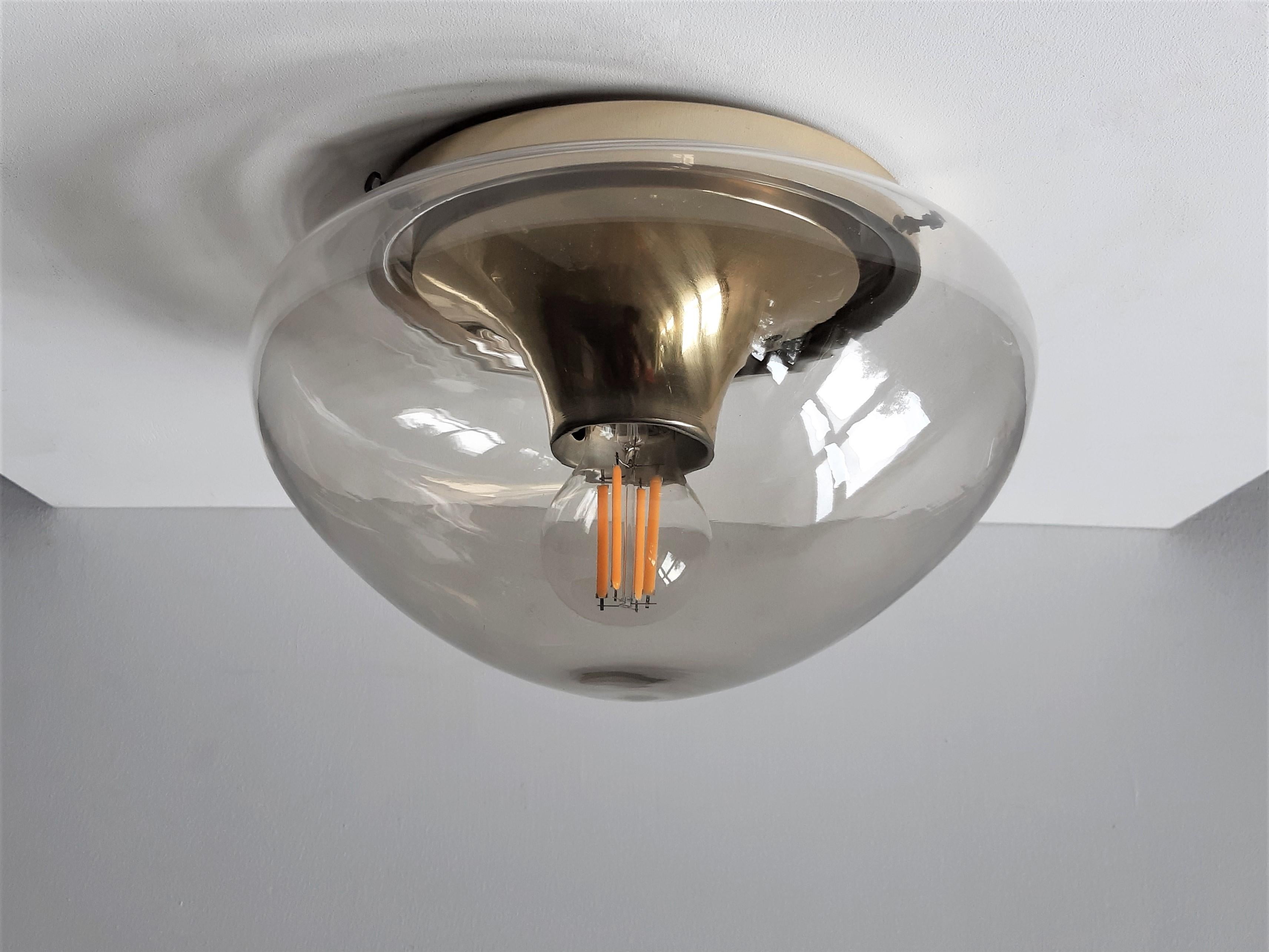 This ceiling lamp or flushmount was made by the Dutch lamp manufacturer Dijkstra in the 1960s-1970s. It has a hand blown glass lampshade. The round aluminum ceiling mount has a conical tube as a light fixture. This lamp gives a very nice warm light