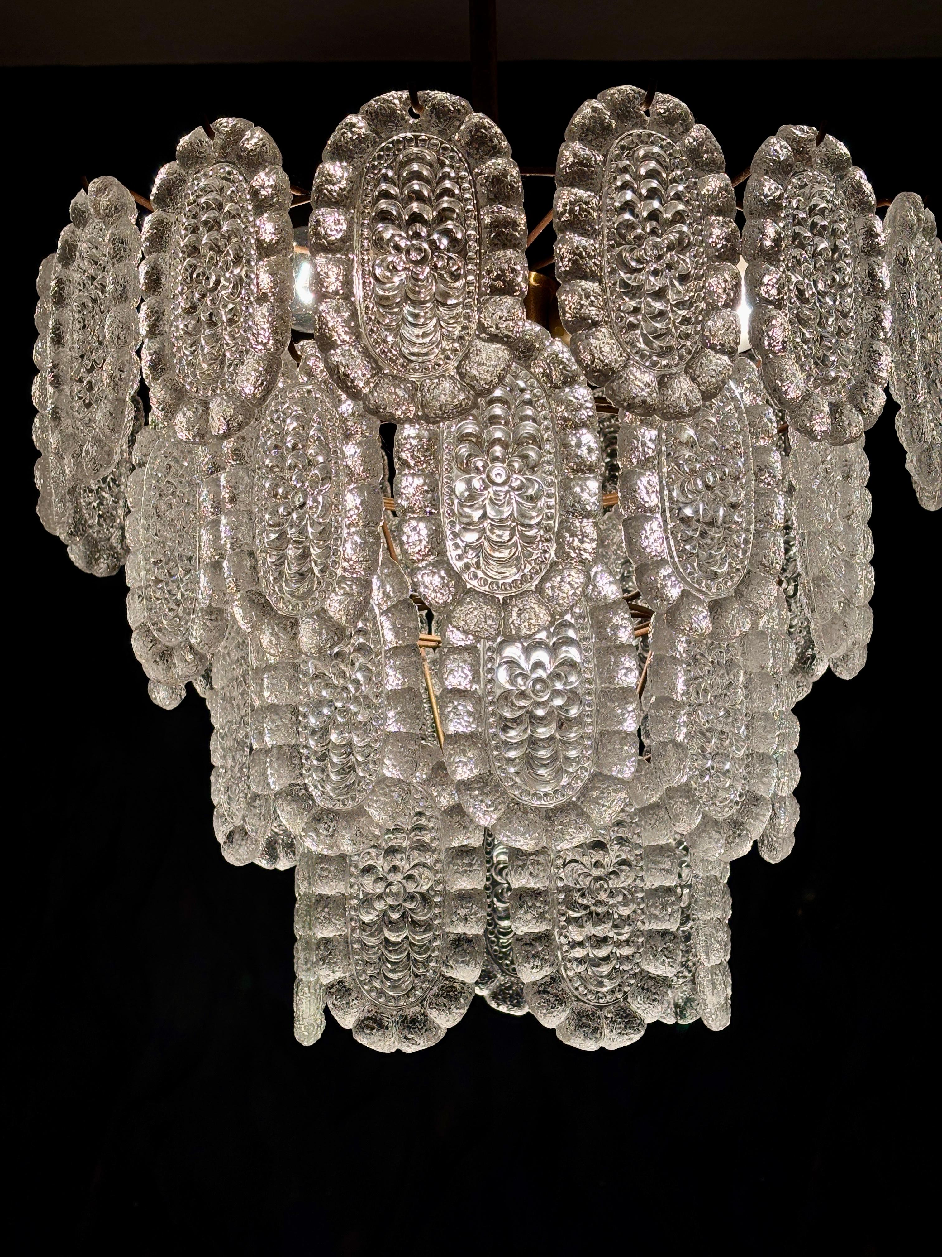 A four-tiered chandelier with shaped glass panels suspended from a metal frame.
The panels are made of pressed crystal glass (43 pieces) and are all identical.

Lightbulbs: 1 x E27 and 3 x E14

Dimensions:
Height without chain: 36 cm (80