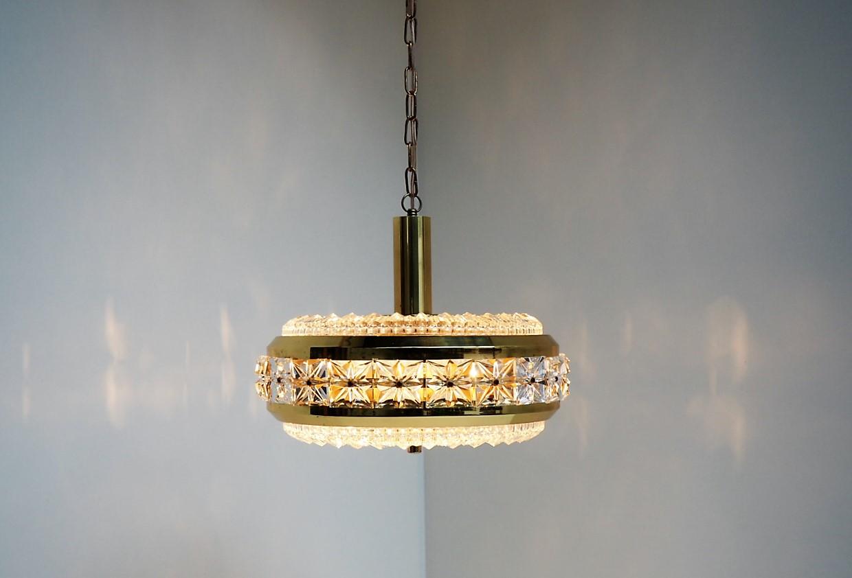 Beautiful gold colored chandelier decorated with square crystal glass pieces made in the 1960s by the Danish company Vitrika with glass from the Swedish glass manufacturer Orrefors.
It gives an incredible good illumination and the light shines