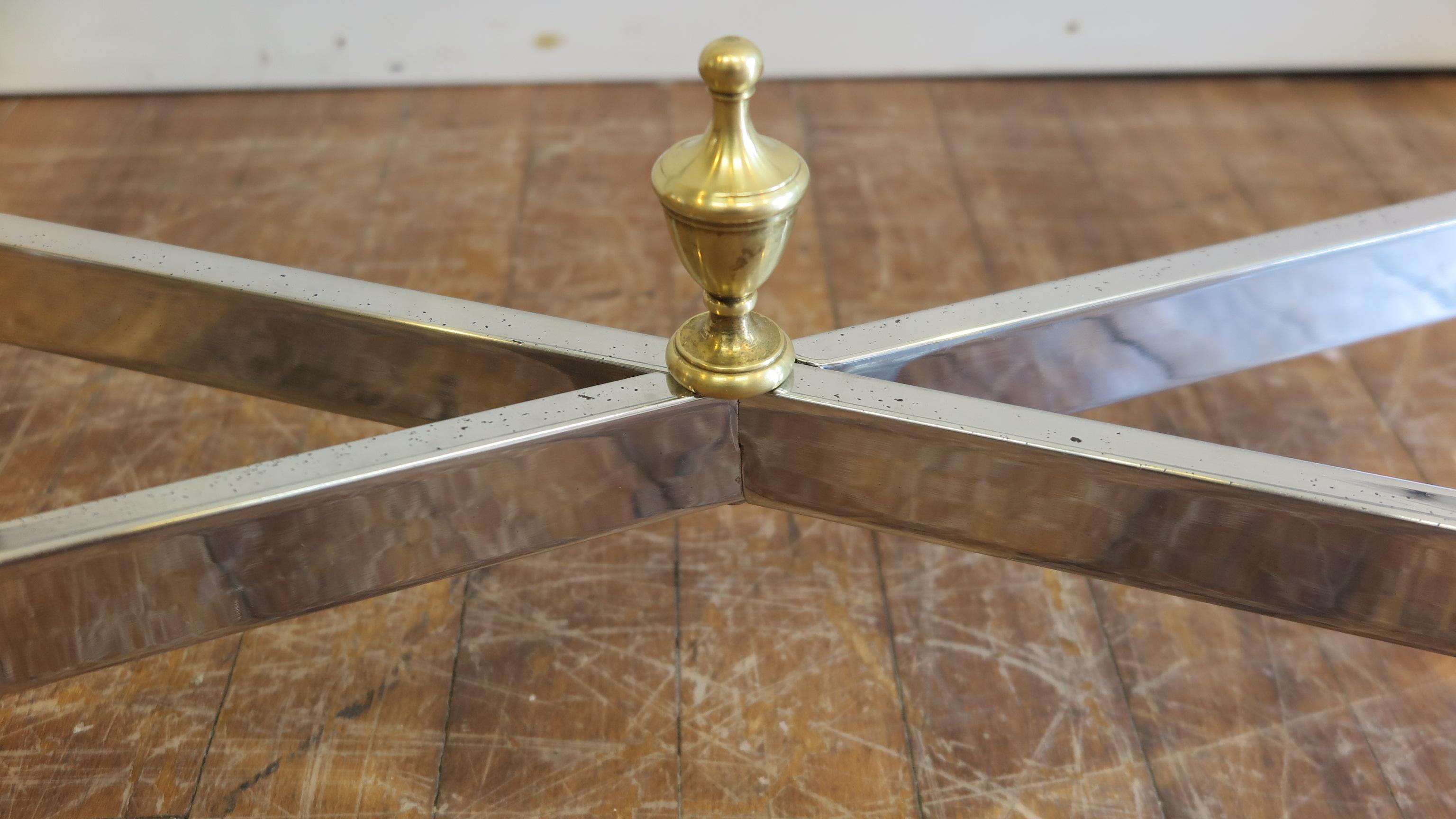 A glass chrome and brass rectangular cocktail table attributed to Maison Jansen . Solid brass details with chrome frame on X-base design. Small chip to one glass corner pictured. Not very noticeable. Light pitting to the chrome in some areas. 1970.