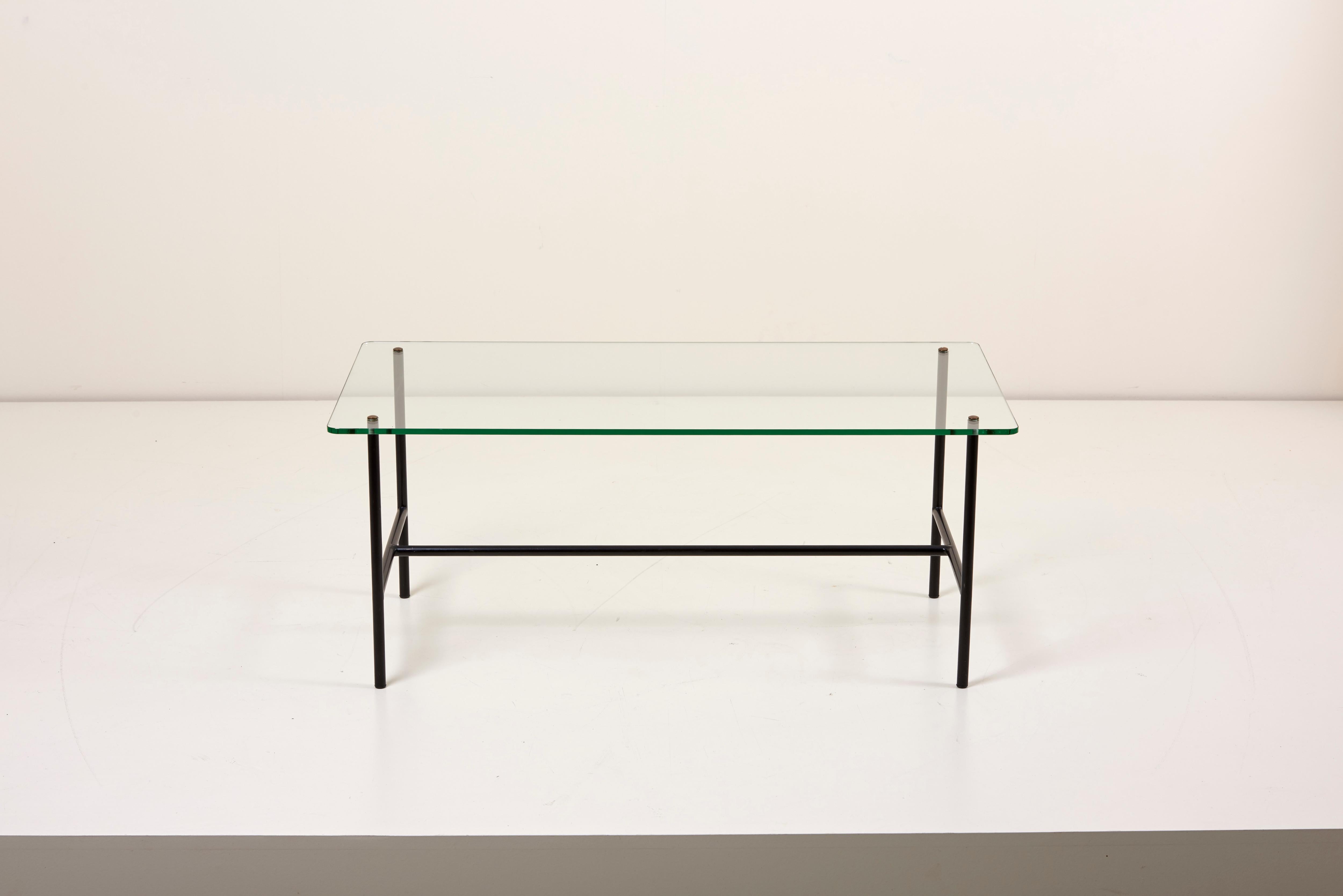 Elegant French coffee table with glass top and iron frame designed by Pierre Guariche for Disderot.
The glass top is pierced and held in place by 4 brass / bronze flat round finials; the top is then cantilevered over the enameled steel frame. Glass