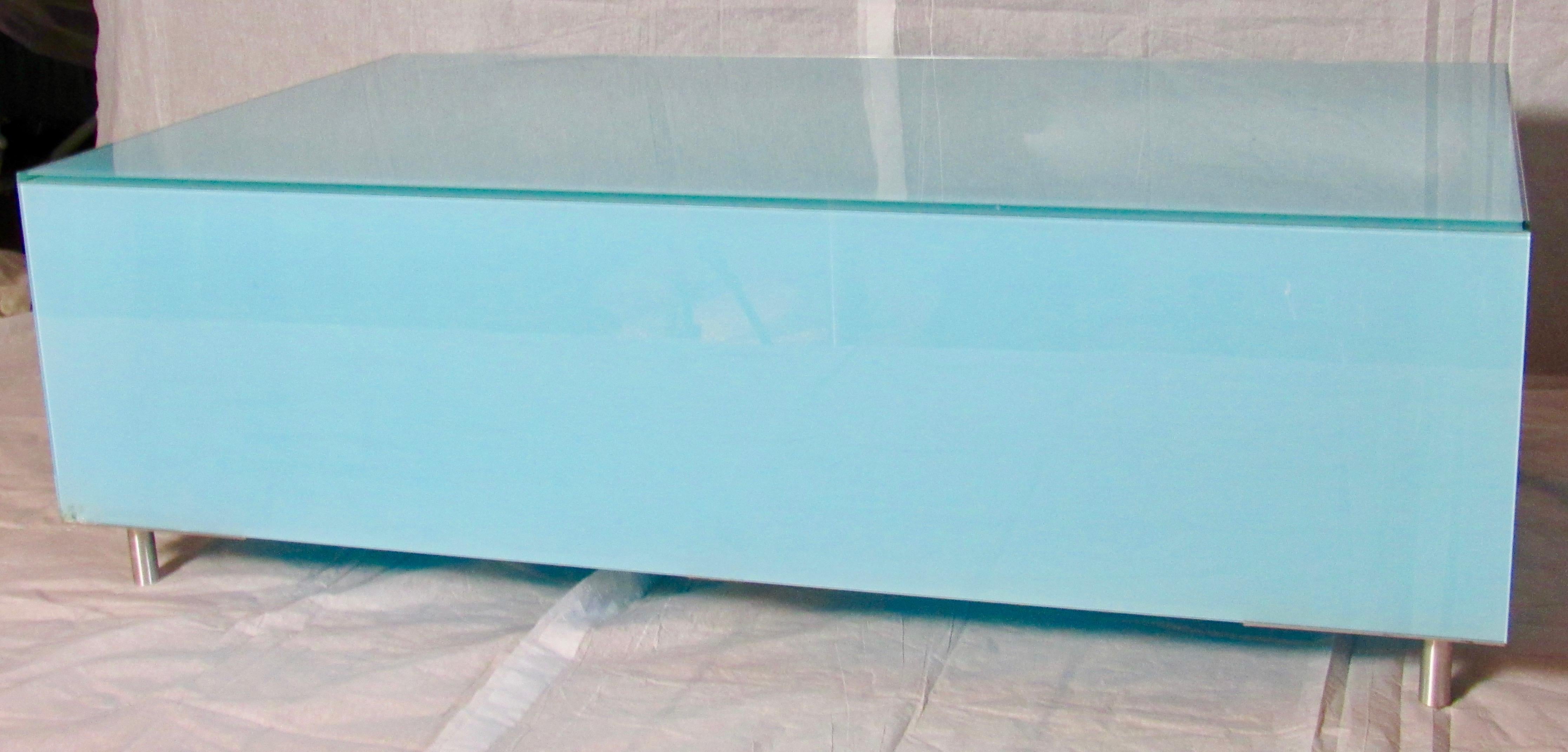 A glass rectangle coffee table in Robin's Egg Blue.
An unusual Minimalist Italian design of reverse painted glass, circa 1970.
Finely crafted glass panels rest on stainless steel feet with aluminum triangles in each corner and a single mid-point