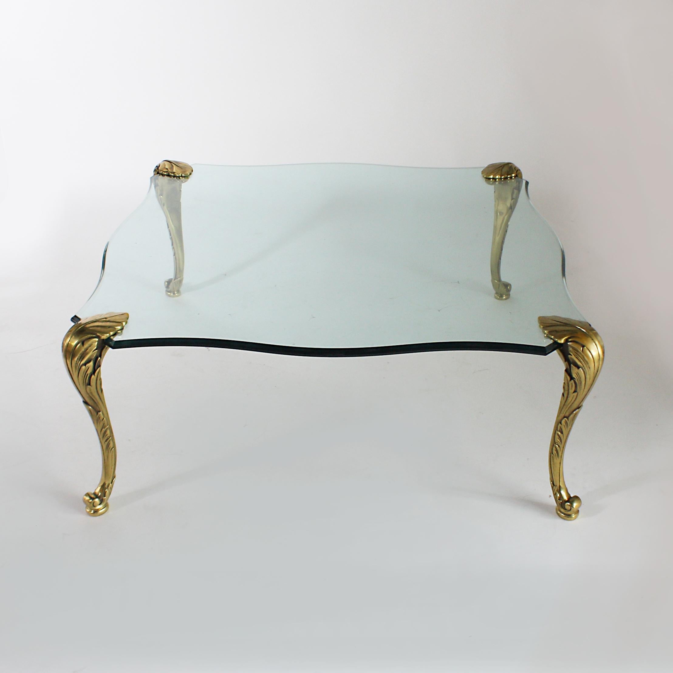 Glass coffee table with brass legs, circa 1940.