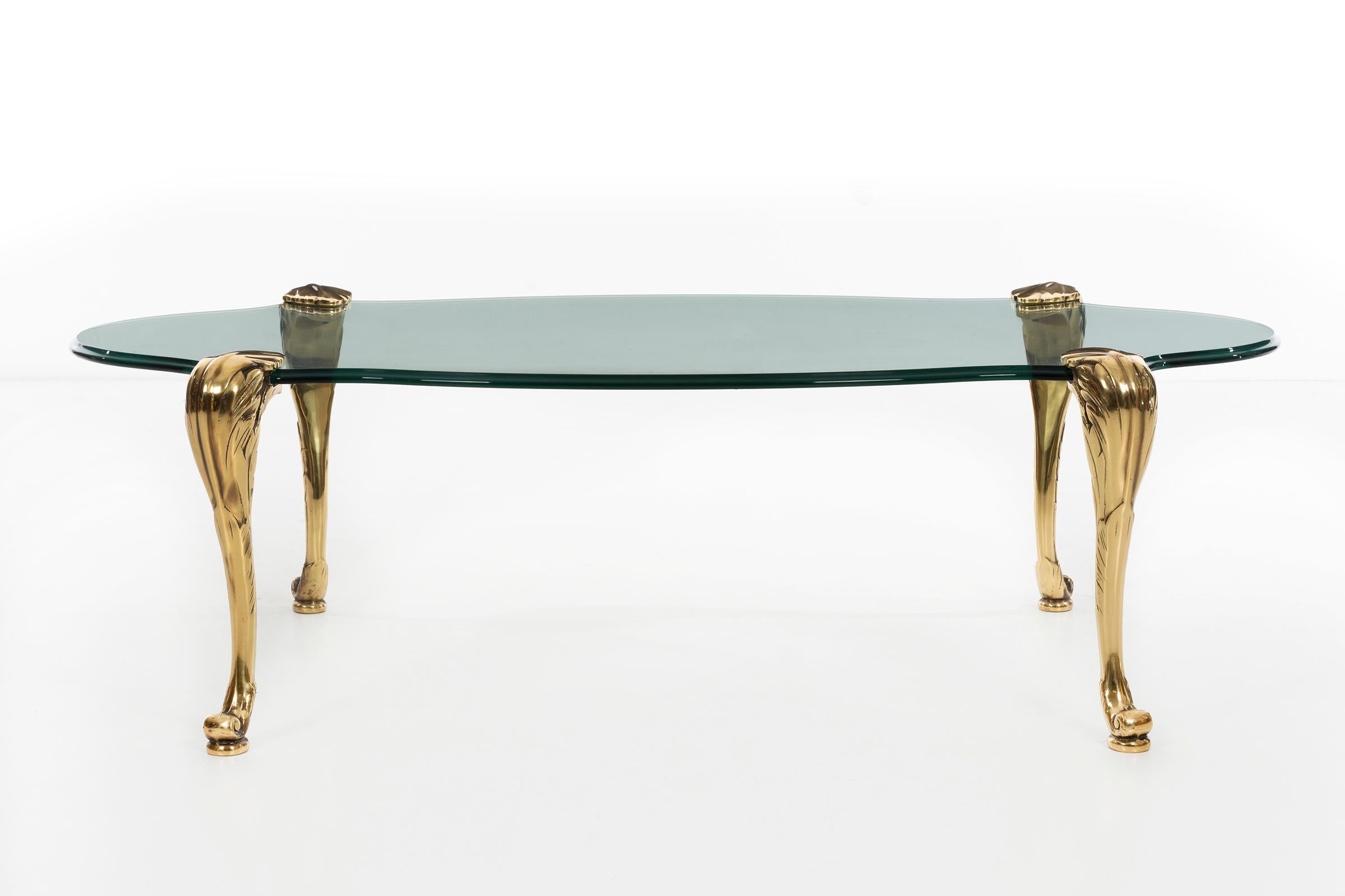 Chapman cocktail table, single sheet of sculpted glass suspended by 4 articulated brass legs with leaf and scroll details.

