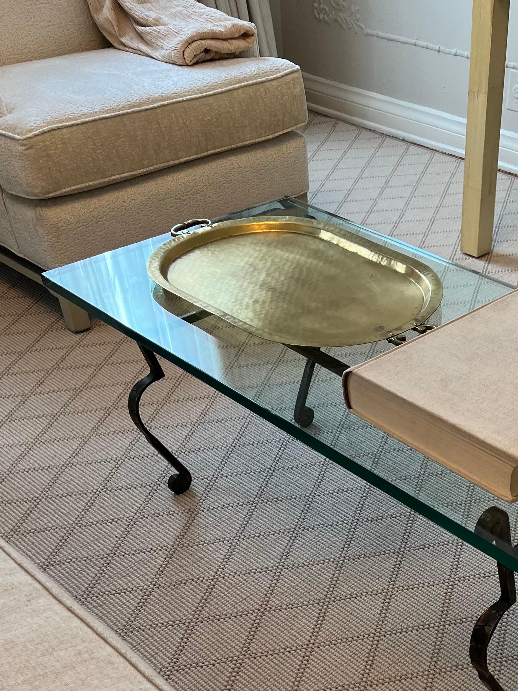 A solid glass surface on this coffee or cocktail table. The base features twisted iron beam and four legs.