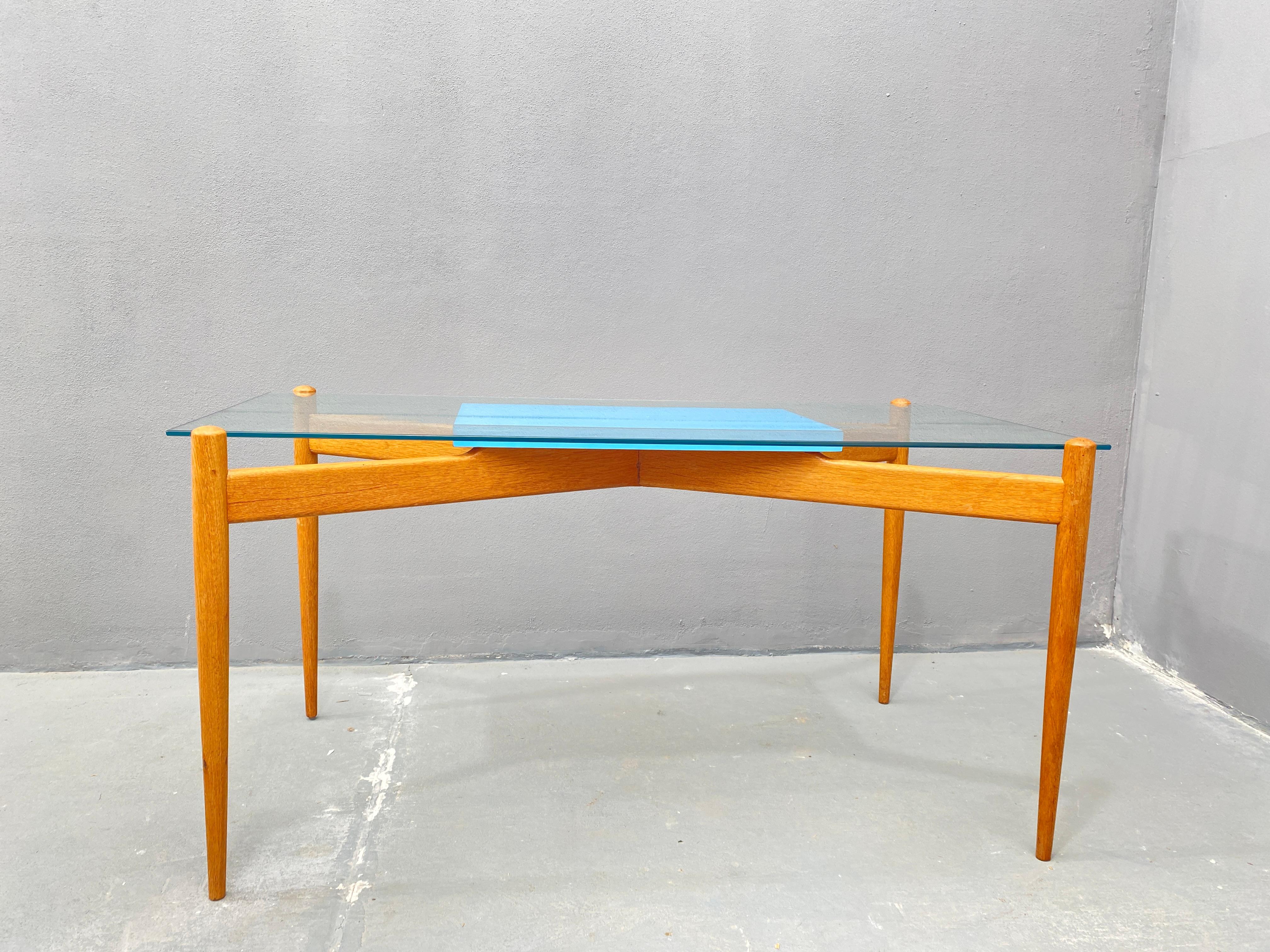 This coffee table with a minimalist design combines a glass tabletop with a beech wooden frame. The transparent glass top gives it a light appearance, while the wooden structure ensures stability and durability. It is suitable for both modern and