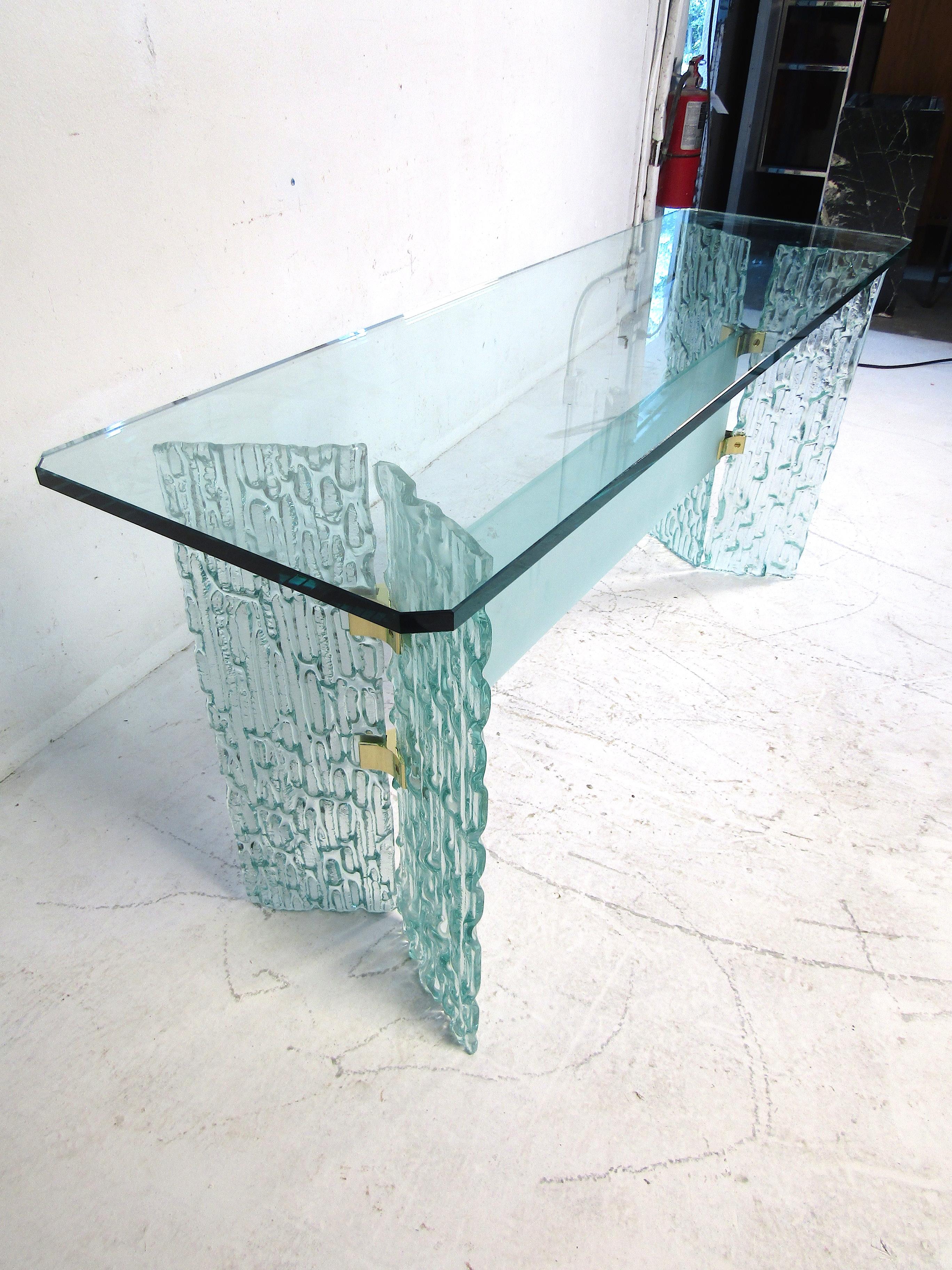 Very unusual console or hallway table. The components are almost entirely made of glass. Interestingly shaped bases with brass hardware support the 3/4 inch pane of beveled glass which serves as the tabletop. Sure to make an impression in any modern