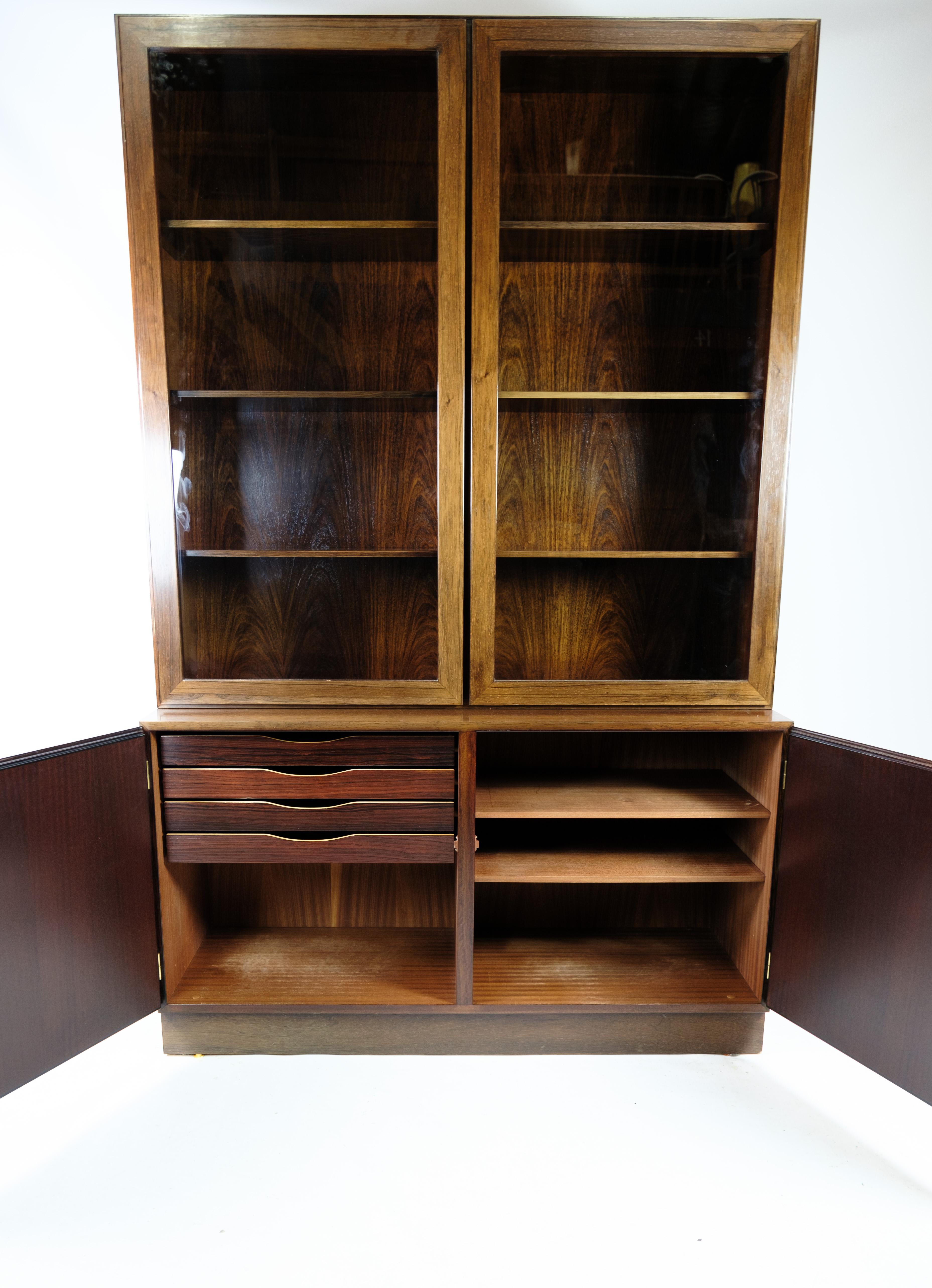 Get a piece of Danish furniture history with this beautiful glass showcase, designed by Omann Junior in rosewood in the 1960s and manufactured at Omann Junior's Møbelfabrik. This display case consists of a lower section with two doors and a glass