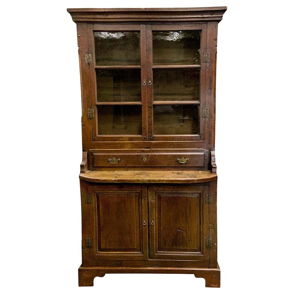 Glass door Russian cupboard, has the original red paint, wavy glass panes, and exposed steel hinges on the upper and lower doors. The scrub pine platform work surface is supported by shaped arms.