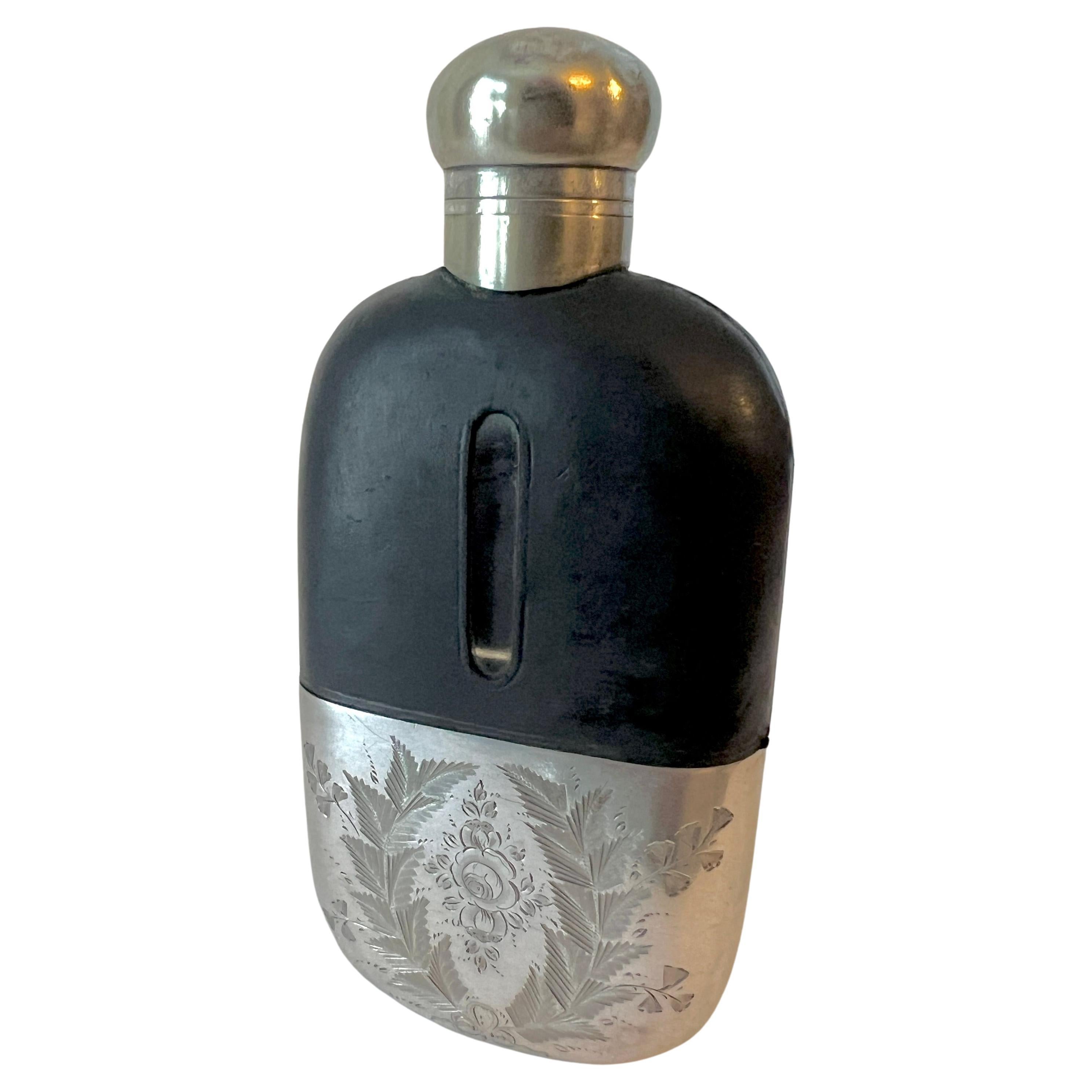 a wonderful Glass Flask with a leather top and Silver plate etched base / drinking cup.

The piece is perfect for the occasional hidden nip and decorative enough to boast to your friends or as a decorative piece.  The top portion is leather with a