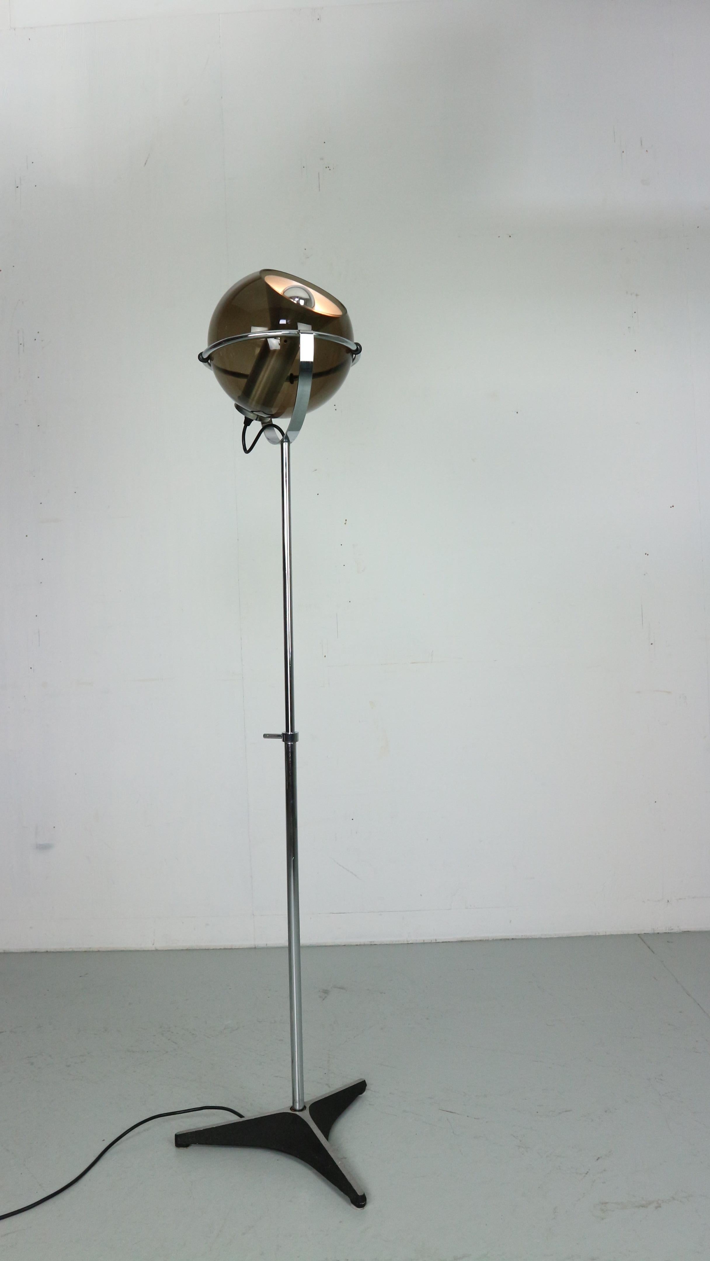 This beautiful 'Globe D-2000' floor lamp was designed by Frank Ligtelijn for Raak Amsterdam in the late 1950's. It has a smoked glass globe, (no chips) with an aluminum reflector and lamp holder, standing on a chromed metal adjustable rod and cast