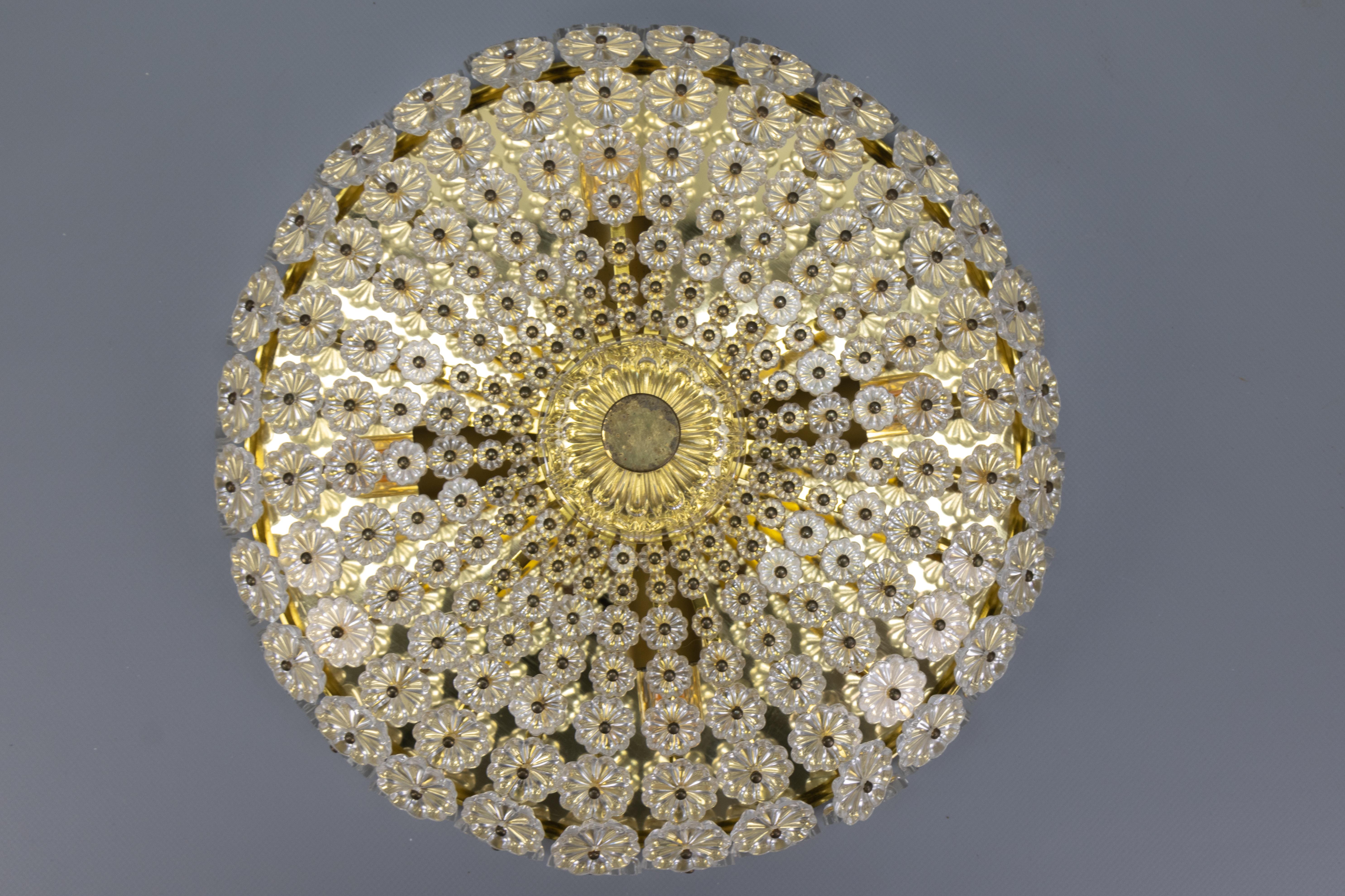 Questa imponente e compatta plafoniera del periodo Space Age o Stejnar è stata progettata da Emil Stejnar (Austria) per l'azienda H. Richter negli anni '50. La lampada da soffitto presenta una lastra e una struttura in ottone, ricoperta di fiori di