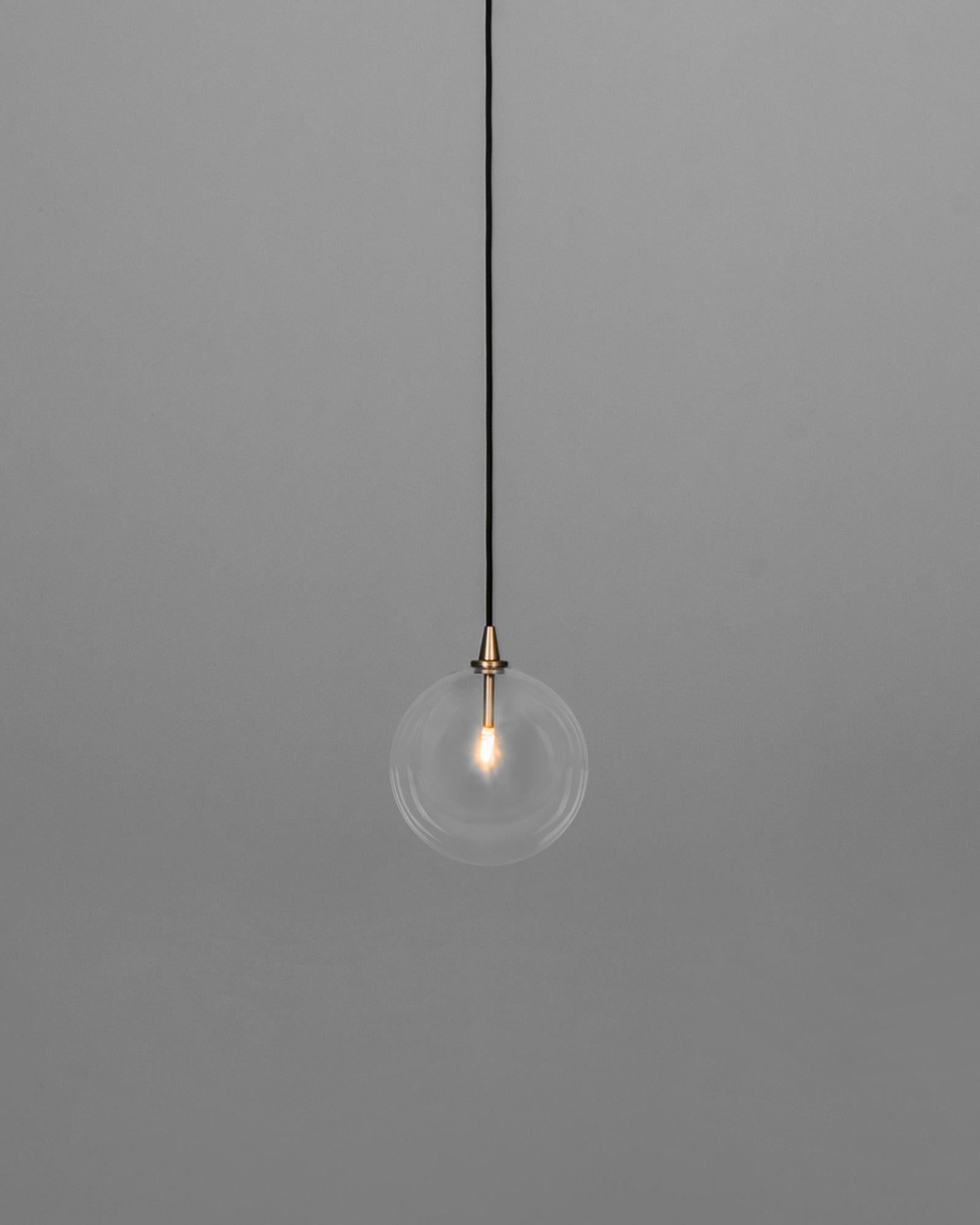 With pristine simplicity, a shining bubble of borosilicate glass hangs in effortless suspension. The crystalline clarity of the translucent sphere gifts a spontaneous, ethereal quality, aided by unassuming brass ceiling fixtures.

Schwung