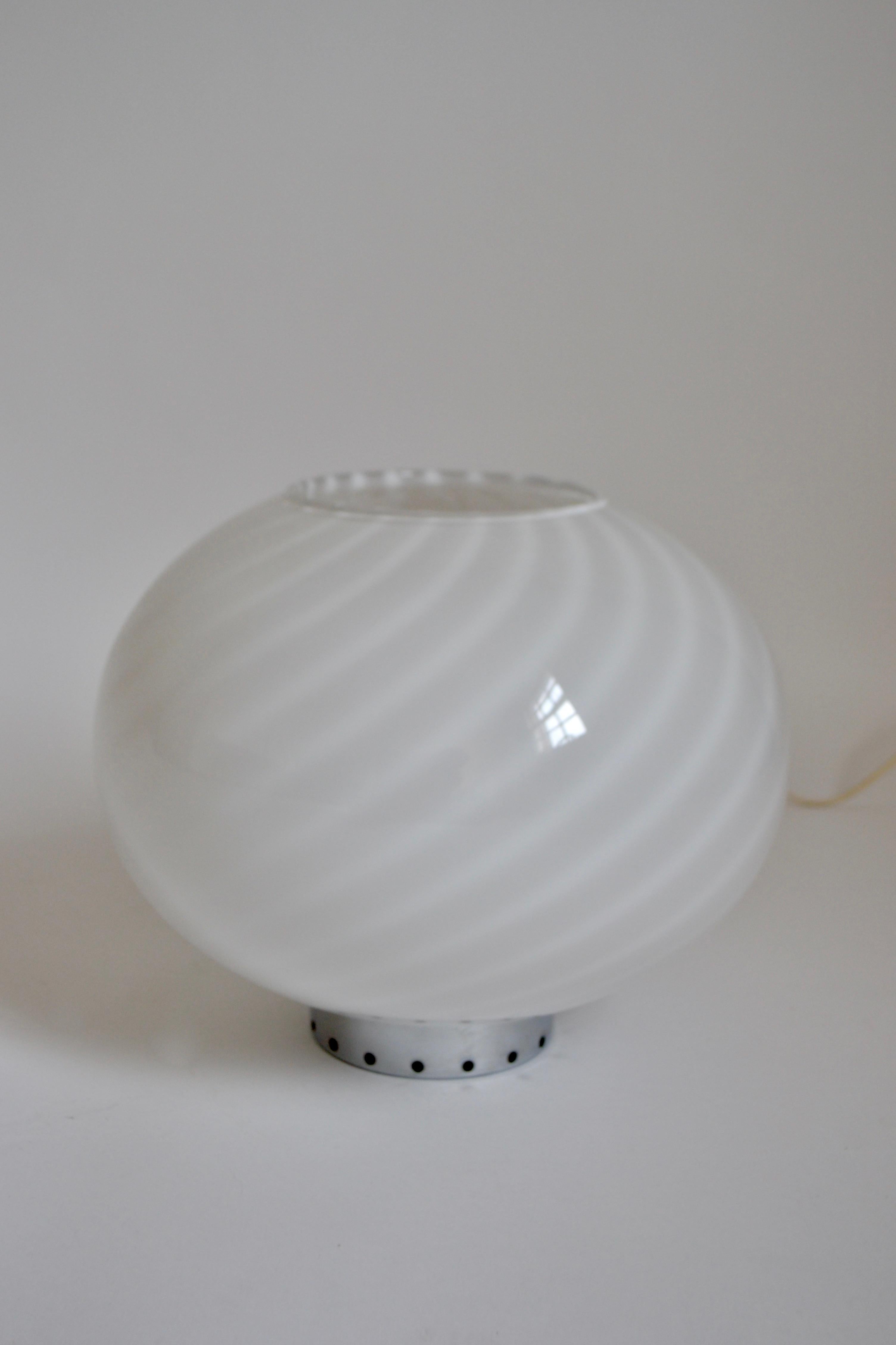 A globular shaped glass table lamp with the iconic swirl by Murano on a chrome base. EU plug.