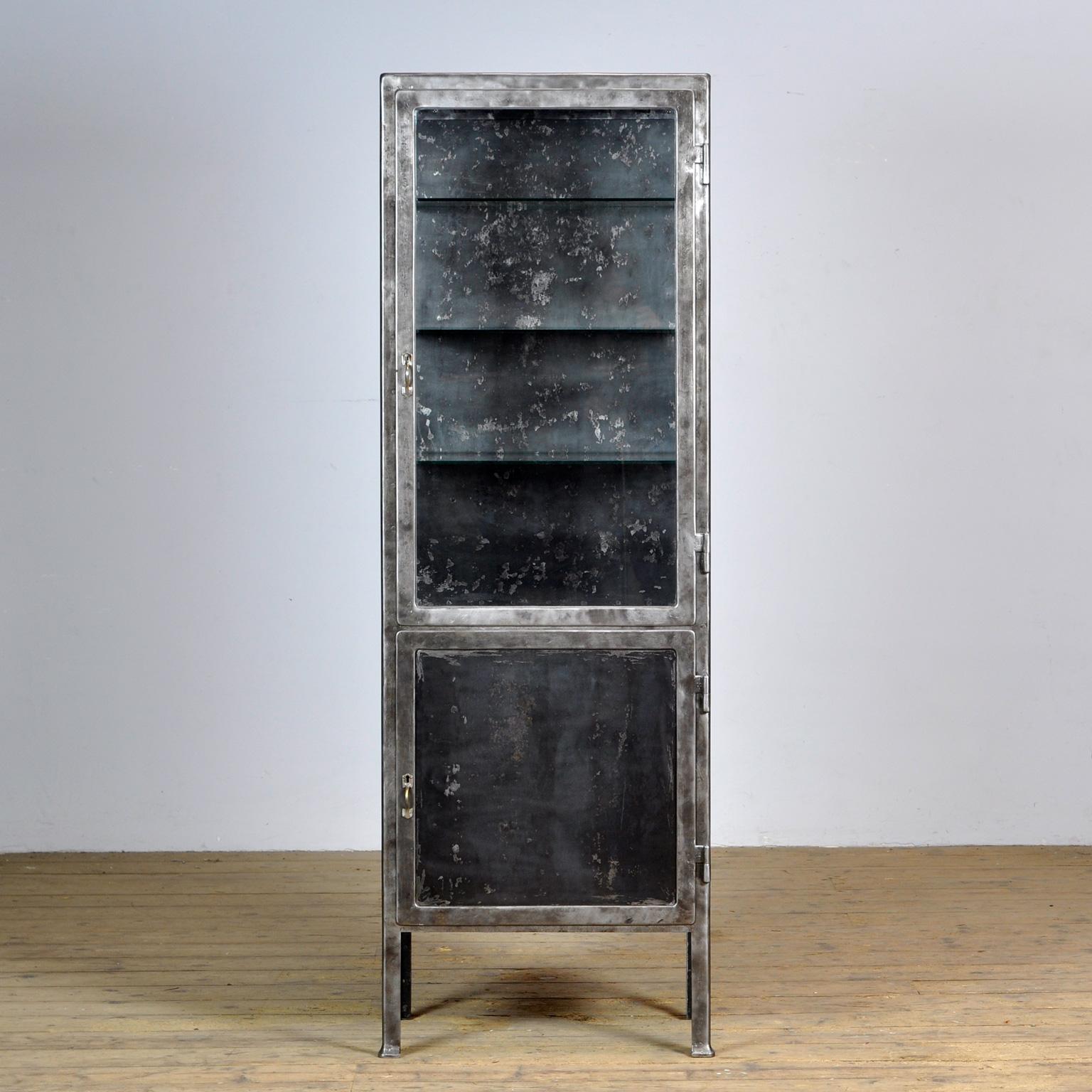 Medical cabinet made of iron and glass. The cabinet is from the 1930s and was produced in Hungary. The cabinet is stripped down to the metal and finished with a transparent lacquer. The cabinet comes with 3 glass shelves. The shelves in the upper