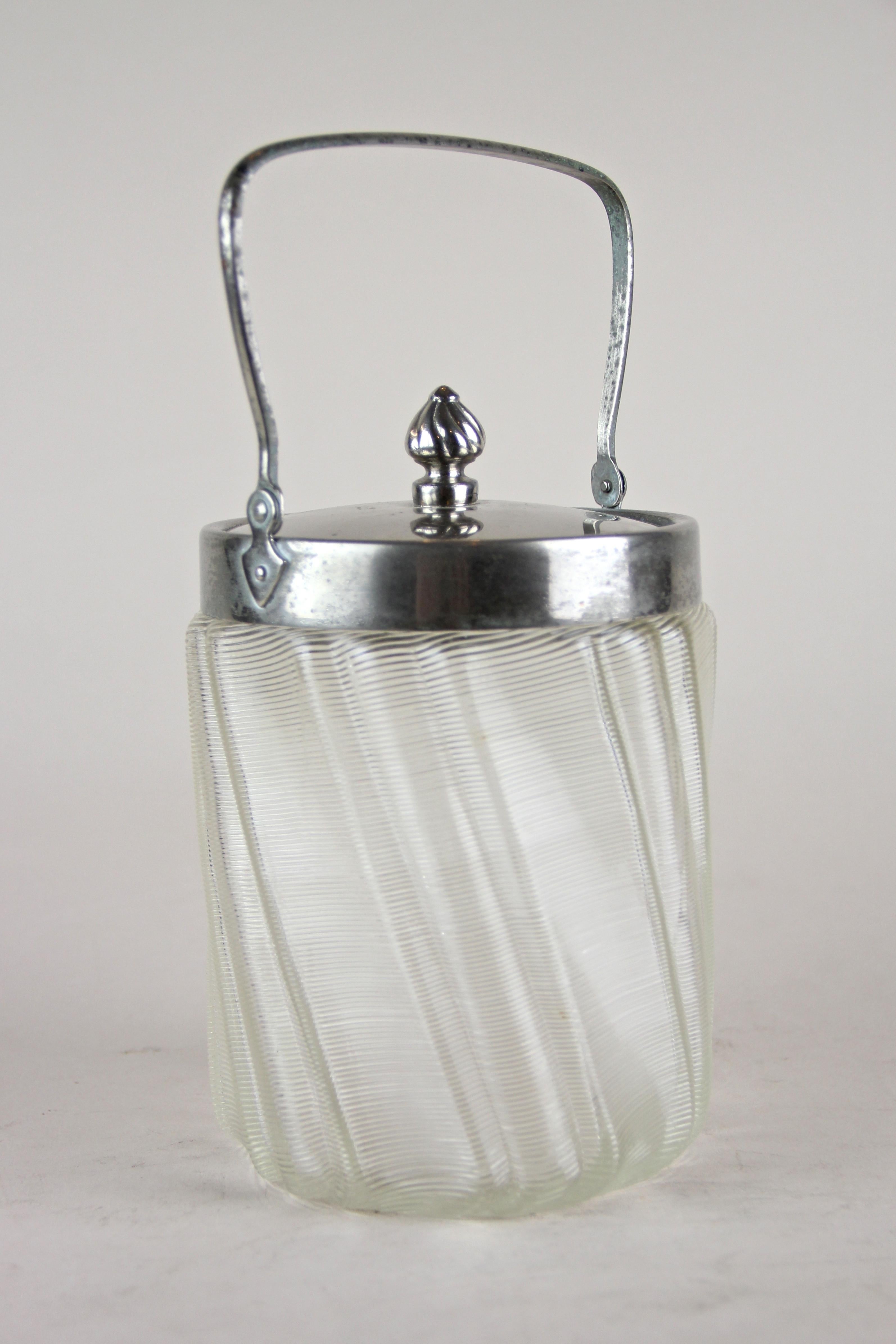 Lovely glass jar with chromed lid from the early 20th century out of Austria. The beautiful shaped glass body looks like it has been twisted and shows an artful surface with glass threads. The removable chrome lid with a nice little cone on it keeps