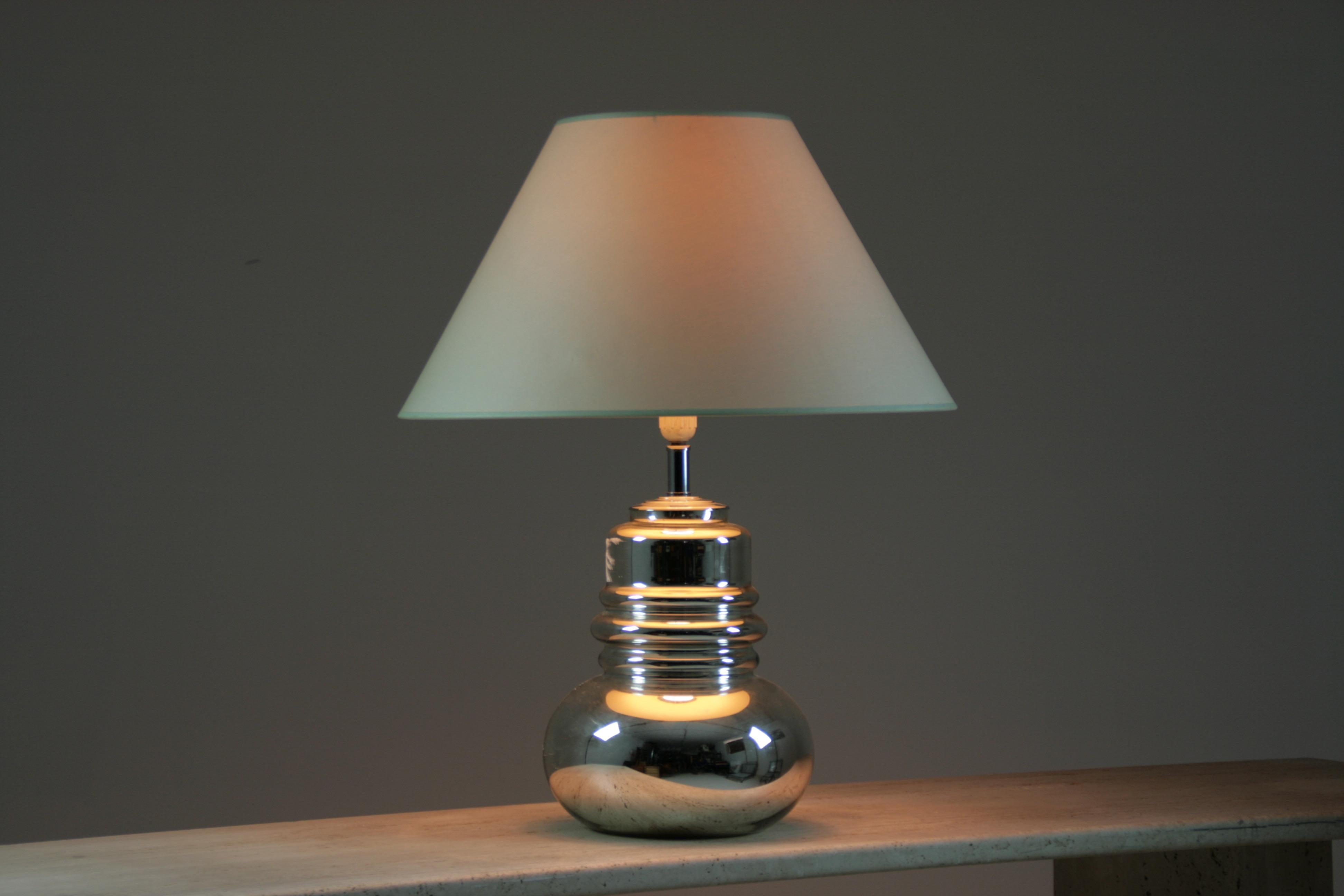 Lampe de table en verre datant des années 1970. Le principe consiste à fixer une fine feuille d'argent sous le verre pour lui donner un effet métallique, miroir et brillant. Sans aucun doute, cette jolie lampe apportera du style à votre intérieur et