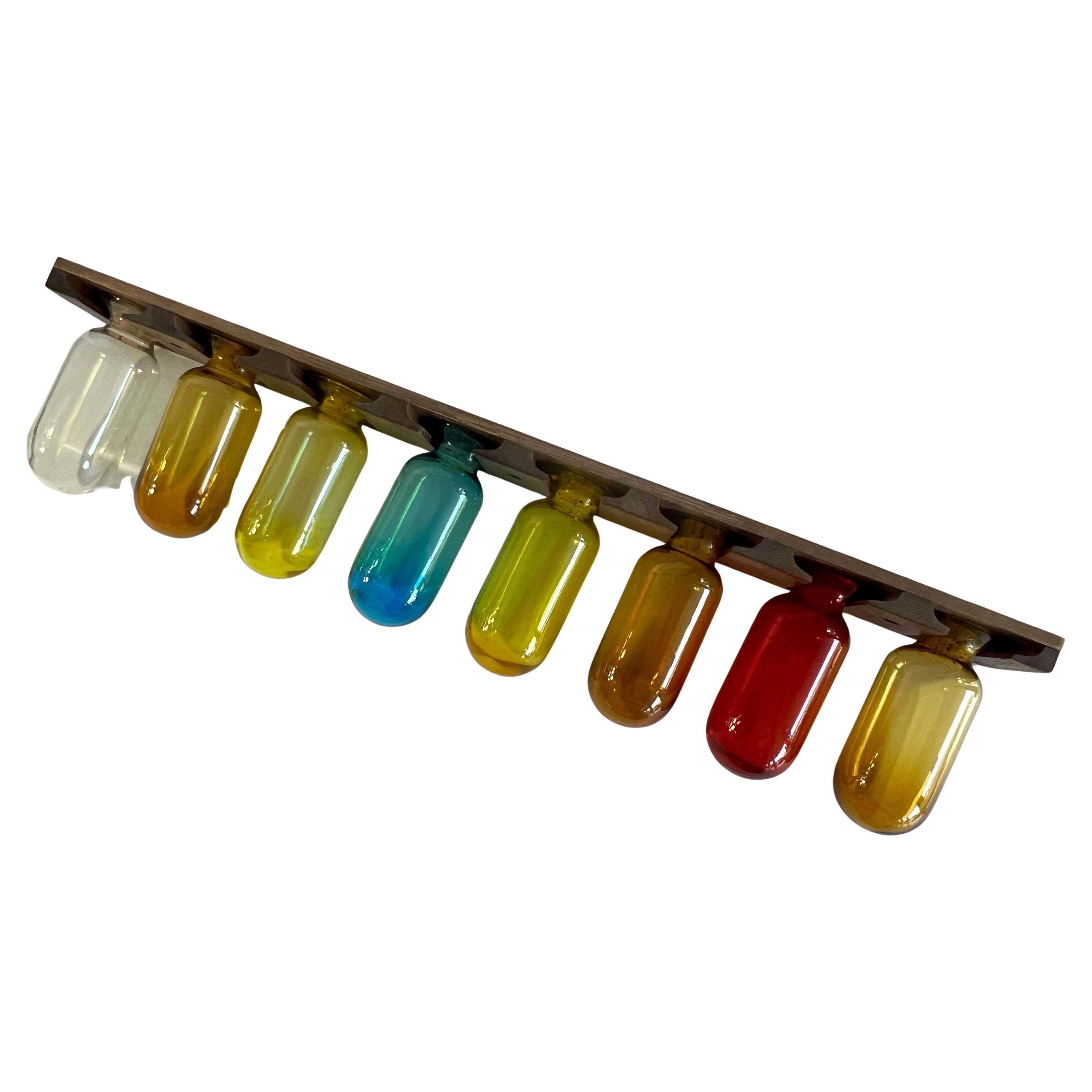 A glass and wood spice rack. The containers are glass with cork stoppers, the rack is wood. 