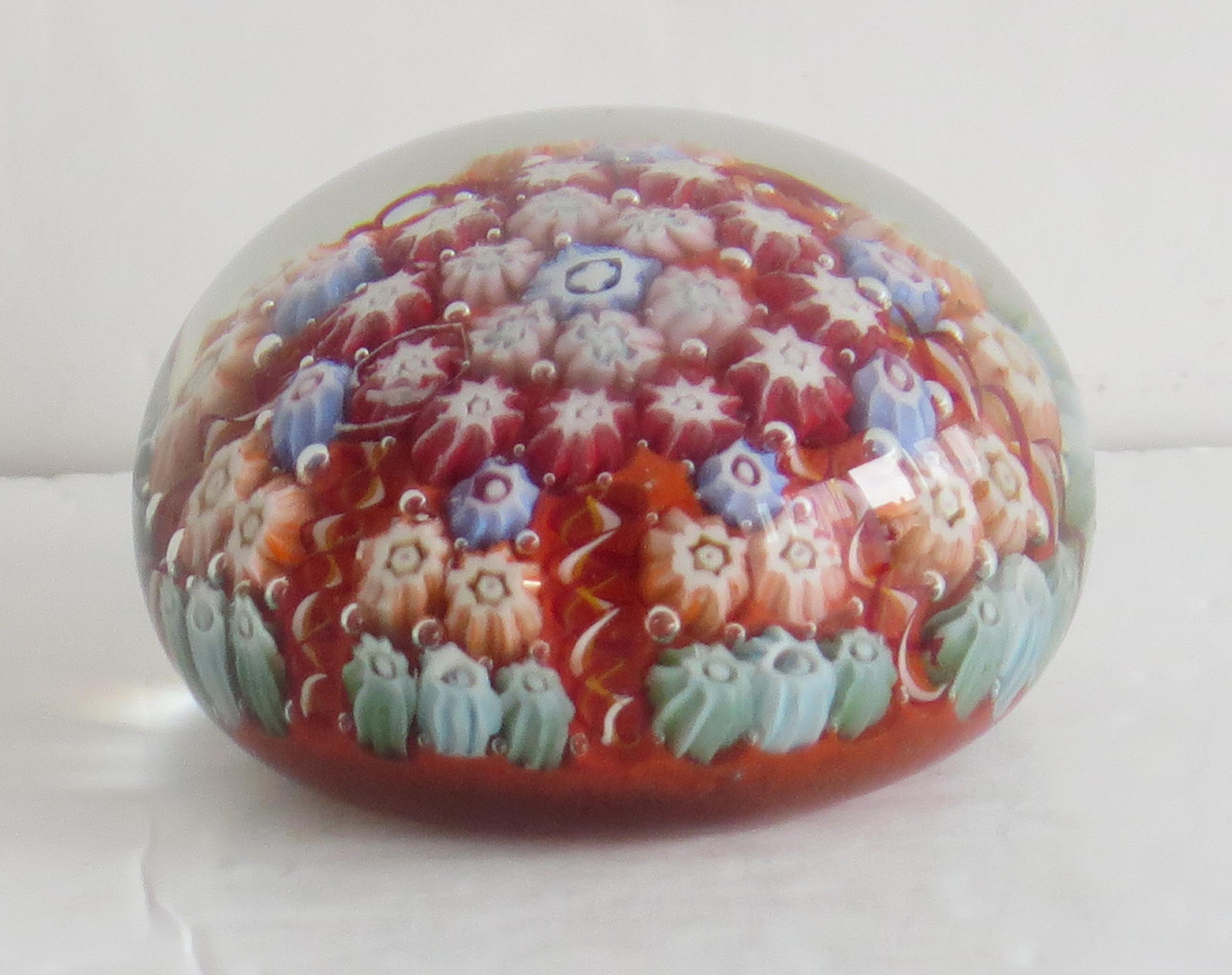 This is a beautiful handmade Millefiori Paperweight by Vasart, Scotland, Circa 1960s.

This paperweight is handmade with a Millefiori, seven spoke radial cane design. The pontil mark to the base has been ground down giving a somewhat matt finish to