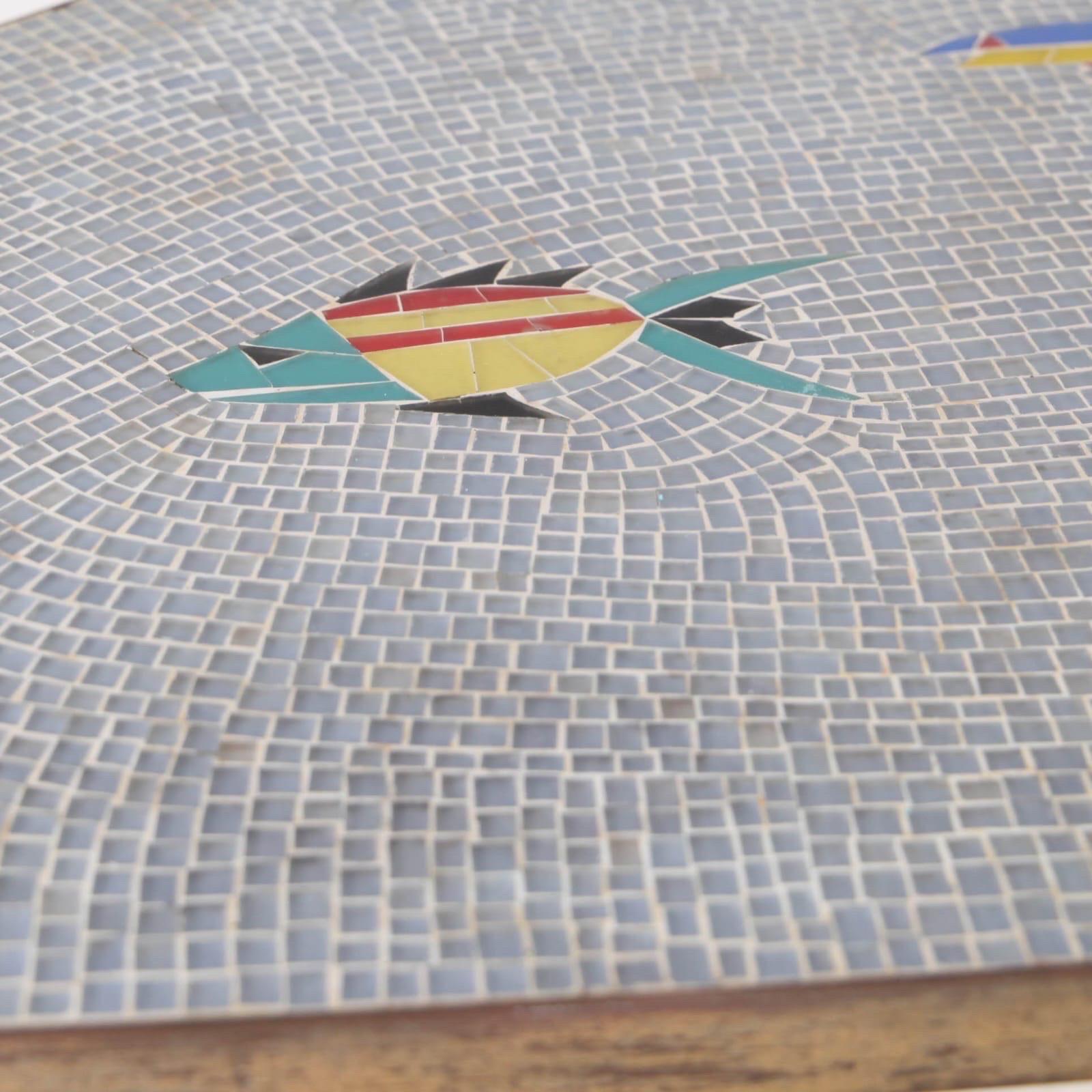 Jolie table basse en mosaïque de verre des années 60 avec des décors de poissons sur le plateau et des pieds en laiton. 
Rare pièce décorative en bon état. 
