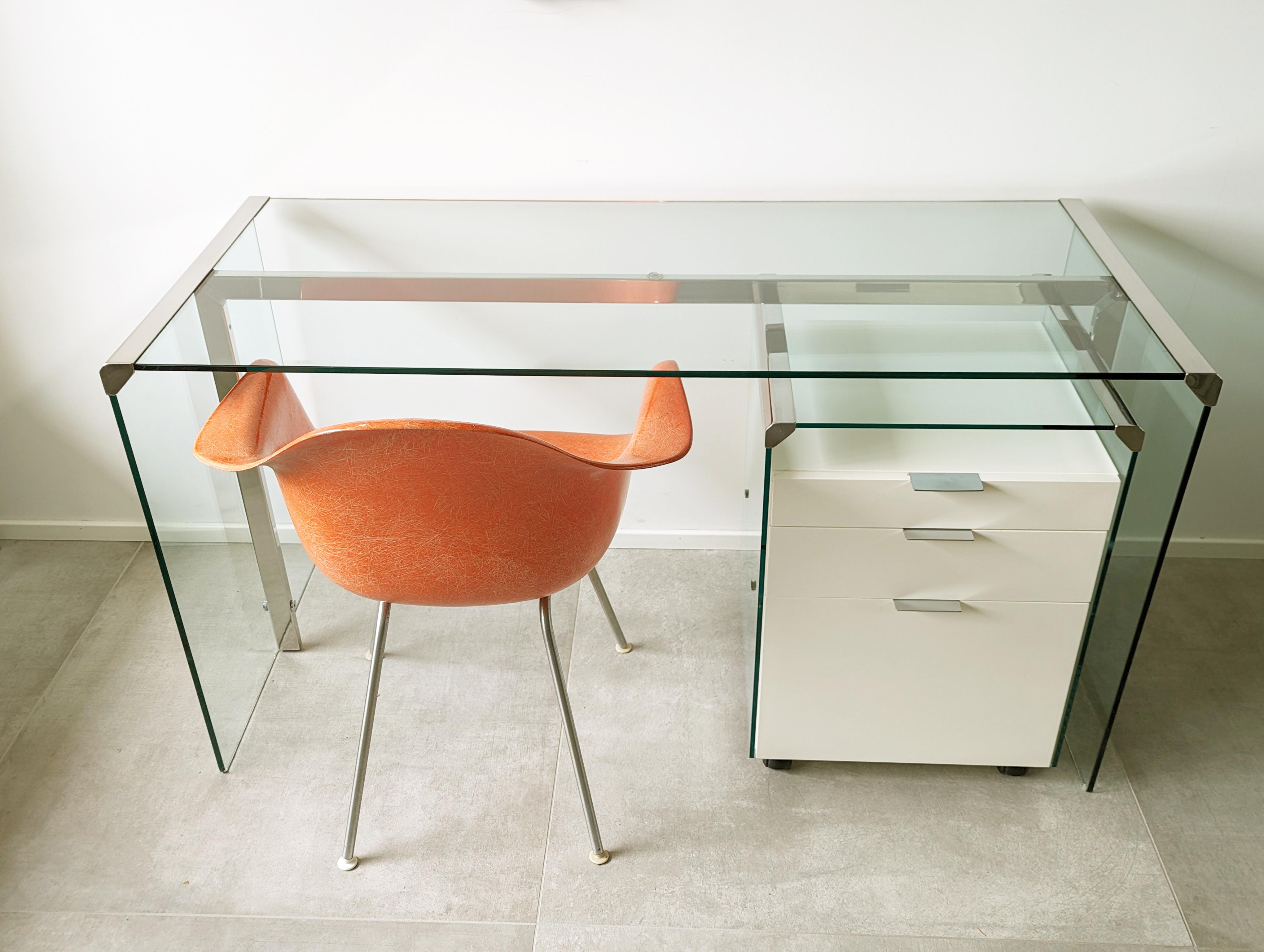 Bureau minimal avec roues  Commode en bois laqué blanc, verre taillé épais et métal chromé.

Bureau minimal et élégant avec commode sur roulettes en bois laqué blanc, verre épais taillé et métal chromé.
Très bon état général : très légères traces