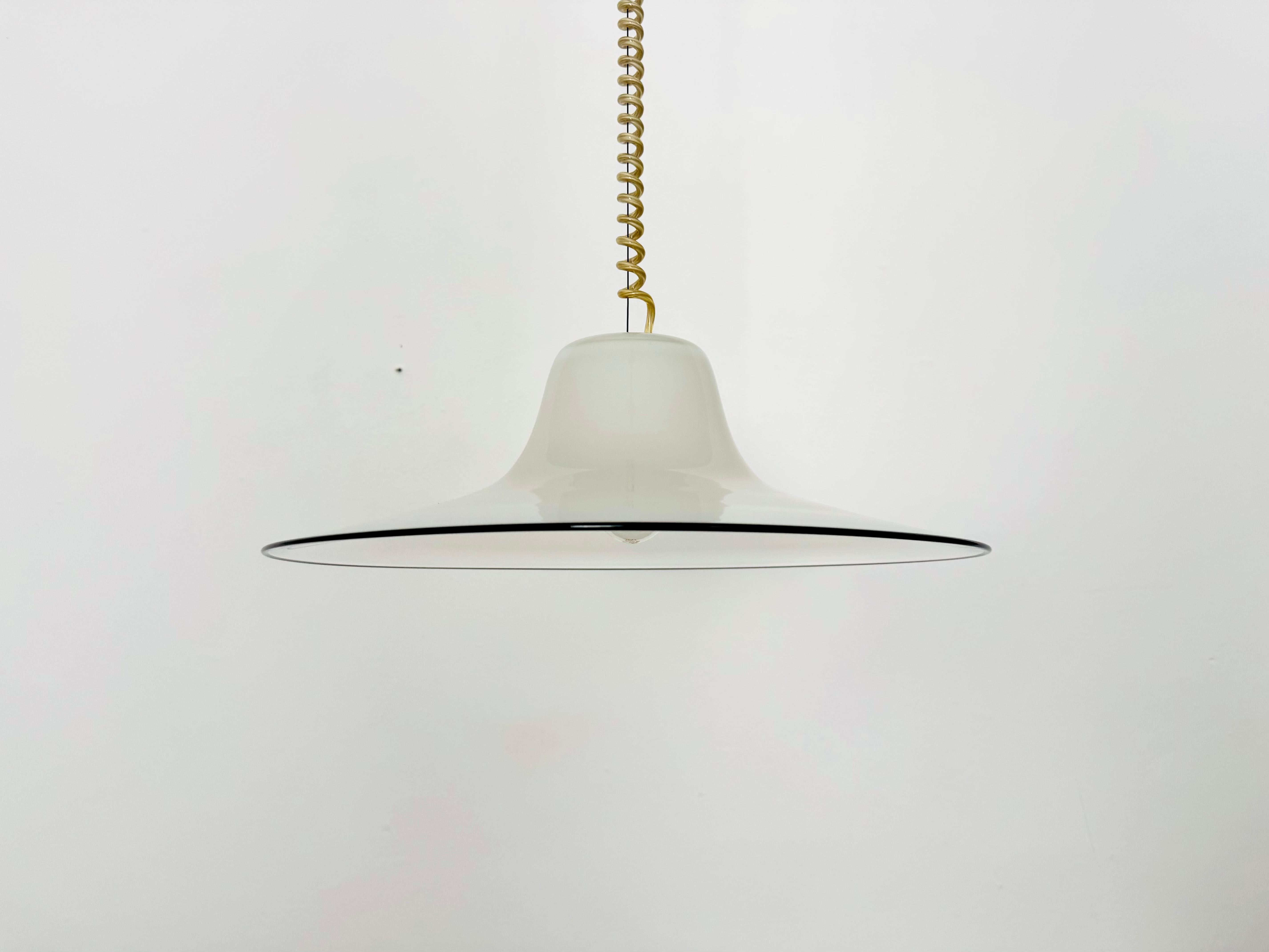 Beeindruckend schöne Murano-Glaslampe aus den 1960er Jahren.
Außergewöhnlich gelungenes Design und sehr hohe Verarbeitungsqualität.
Das milchige Glas und der dekorative schwarze Rand erzeugen ein schönes Licht.

Entwurf: Giusto Toso
Hersteller:
