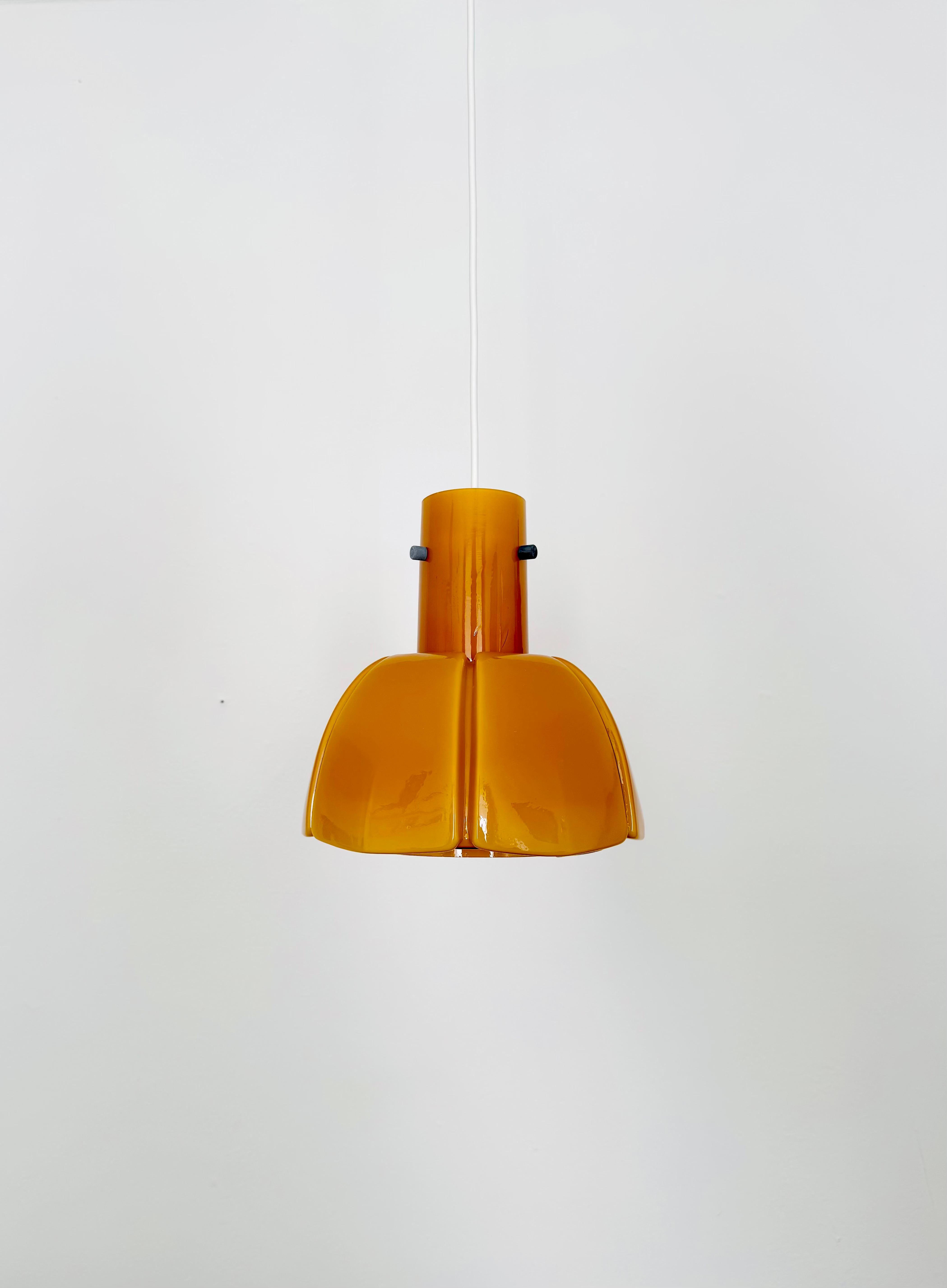 Lampada a sospensione molto bella e rara degli anni '60.
Il vetro soffiato a mano in una tonalità ambrata è un vero e proprio richiamo per gli occhi e ha un design impressionante.
La lampada crea un'atmosfera accogliente e incanta con il suo