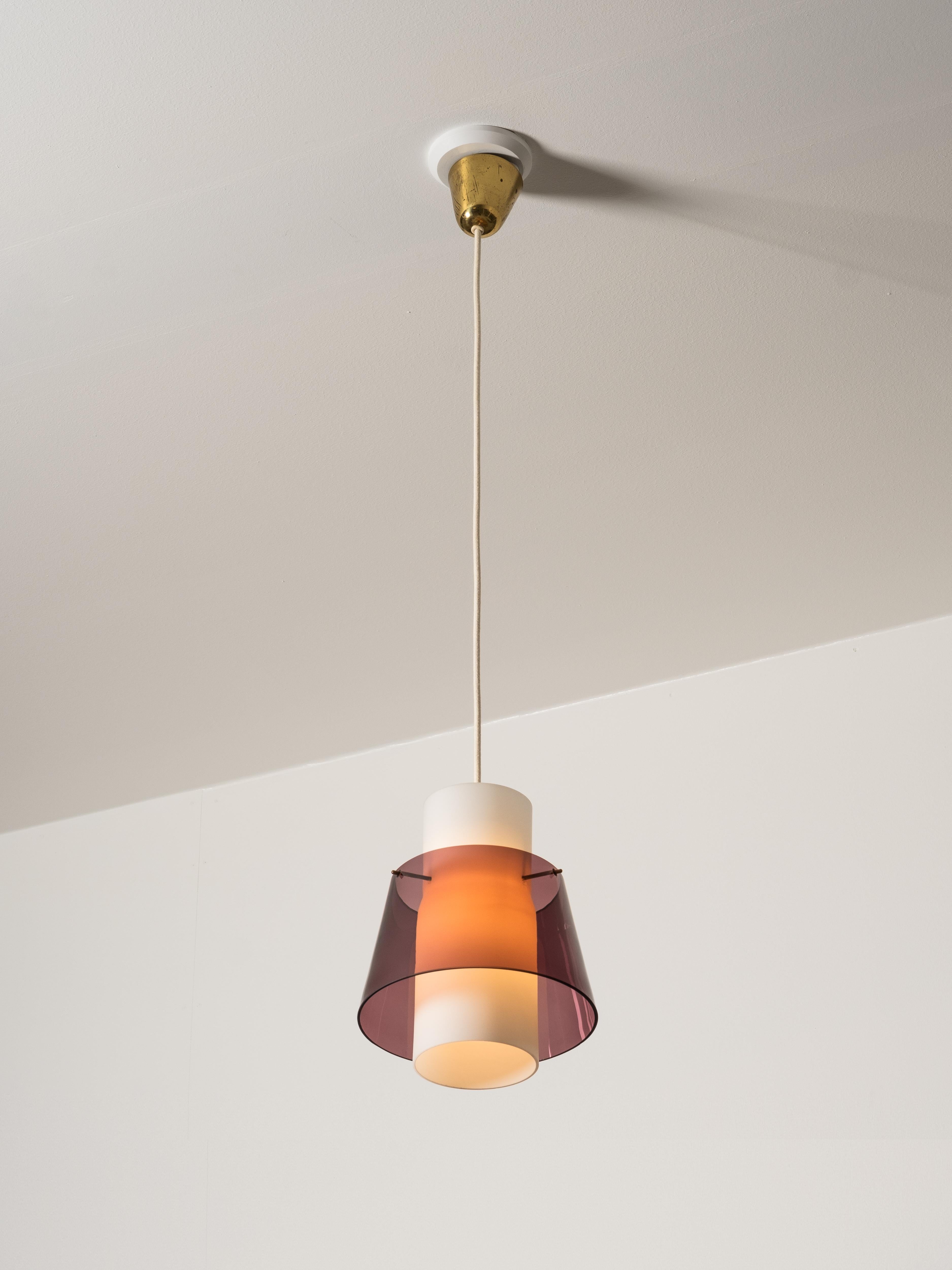 Una lampada a sospensione modernista prodotta da Stockmann negli anni Cinquanta. La lampada combina un nucleo cilindrico in vetro opalino con un paralume esterno in vetro viola intenso, creando un effetto stratificato di luce e colore. La forma è