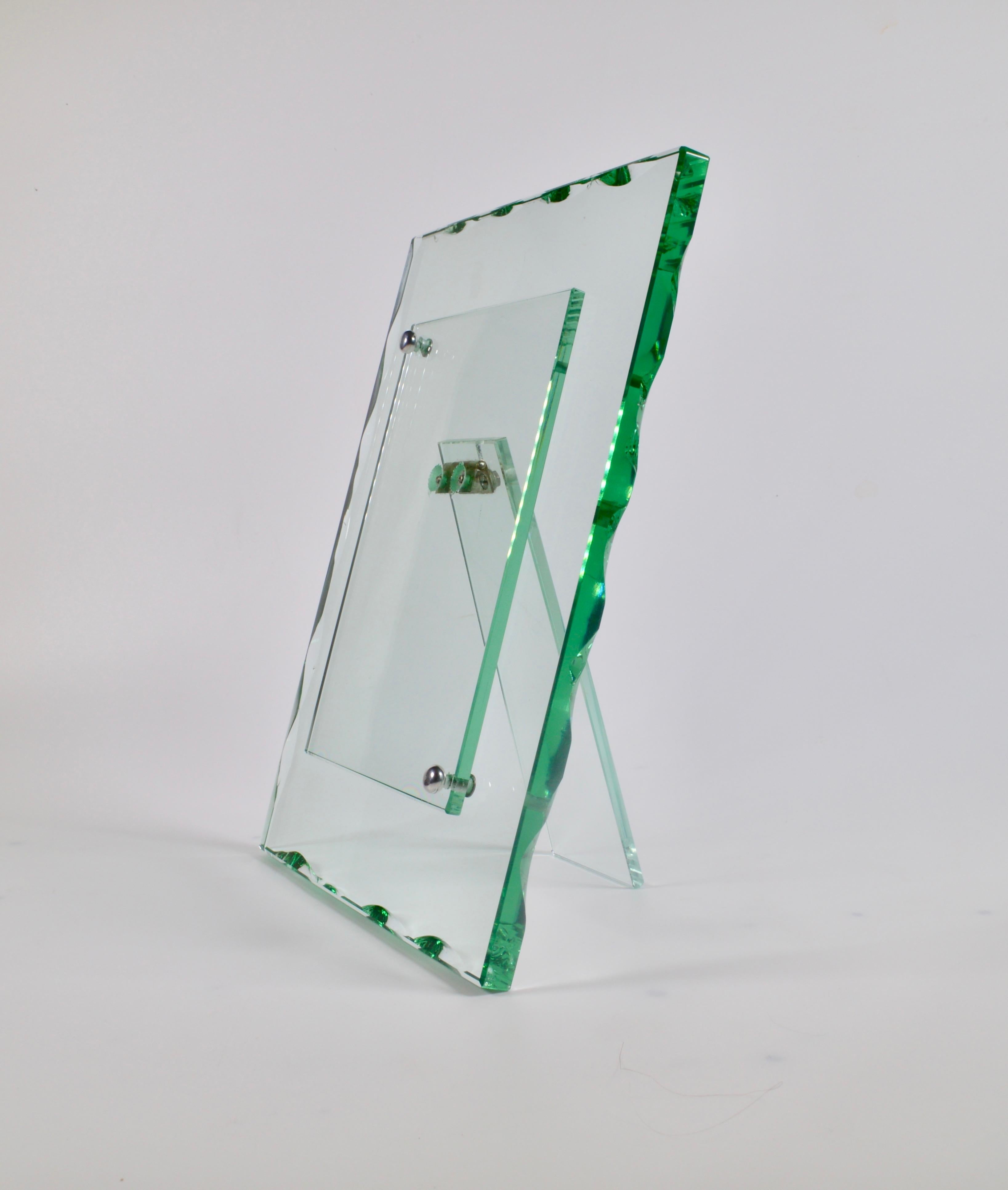 A beautiful cut glass photoframe by Fontana Arte from the 1940s with an indented polished green edge. The front piece is neatly secured with two nickel plated round button screws. 

27.5 x 21