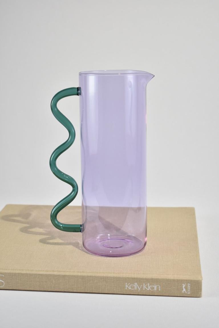 Glass pitcher in lilac with a teal wavy handle. May be used for holding flowers, watering plants, a pitcher for juice or any other use you can think of. Designed by Sophie Lou Jacobsen in New York.

Made of lightweight and durable borosilicate