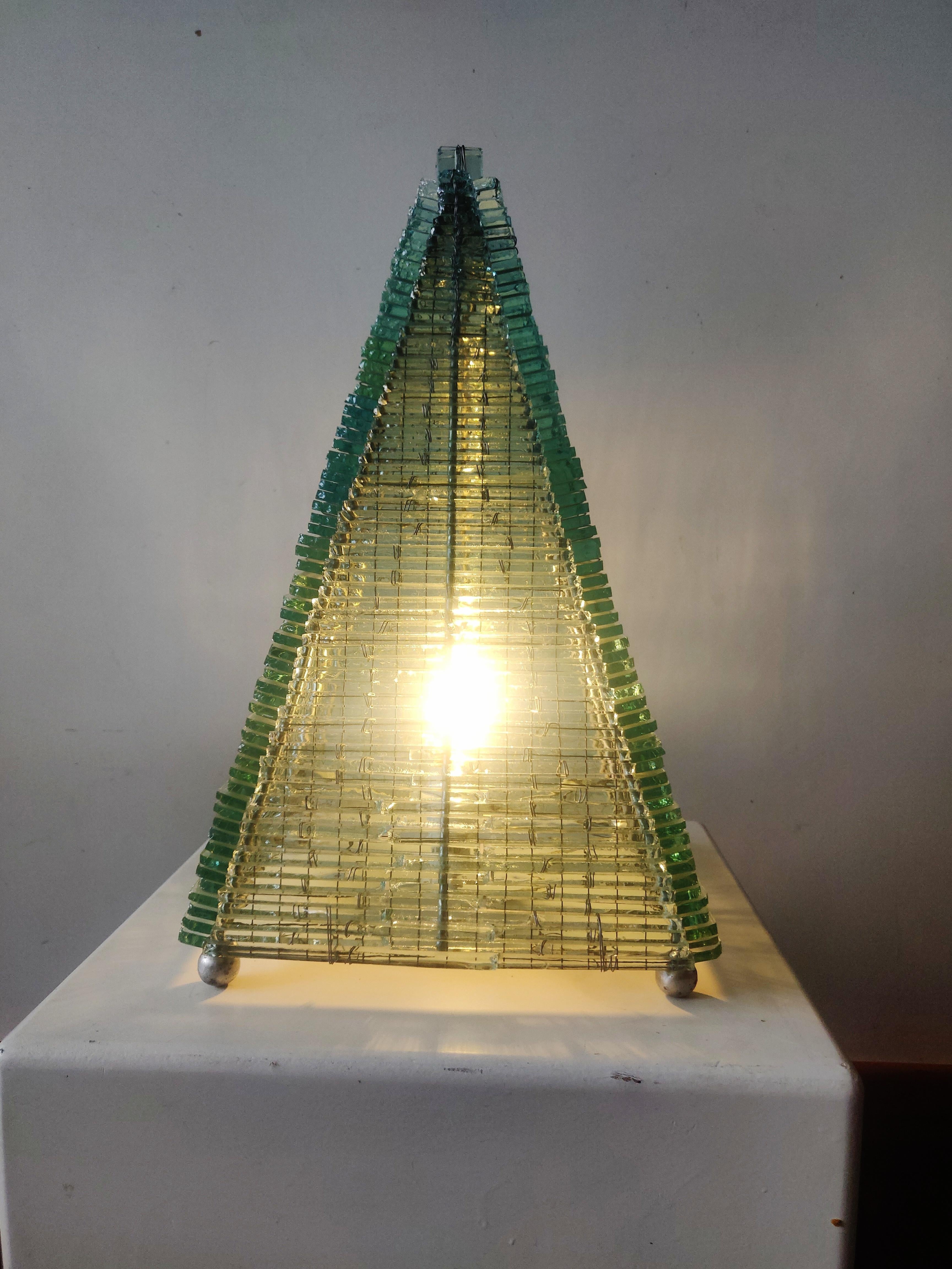 Vintage French Glass pyramid shaped table lamp. Multiple layers of pieces of glass built up in a pyramid shape, hand wired and rests on a metal frame dating from the 1970s 
Functions as a piece of sculpture as well as a table lamp. The green glass