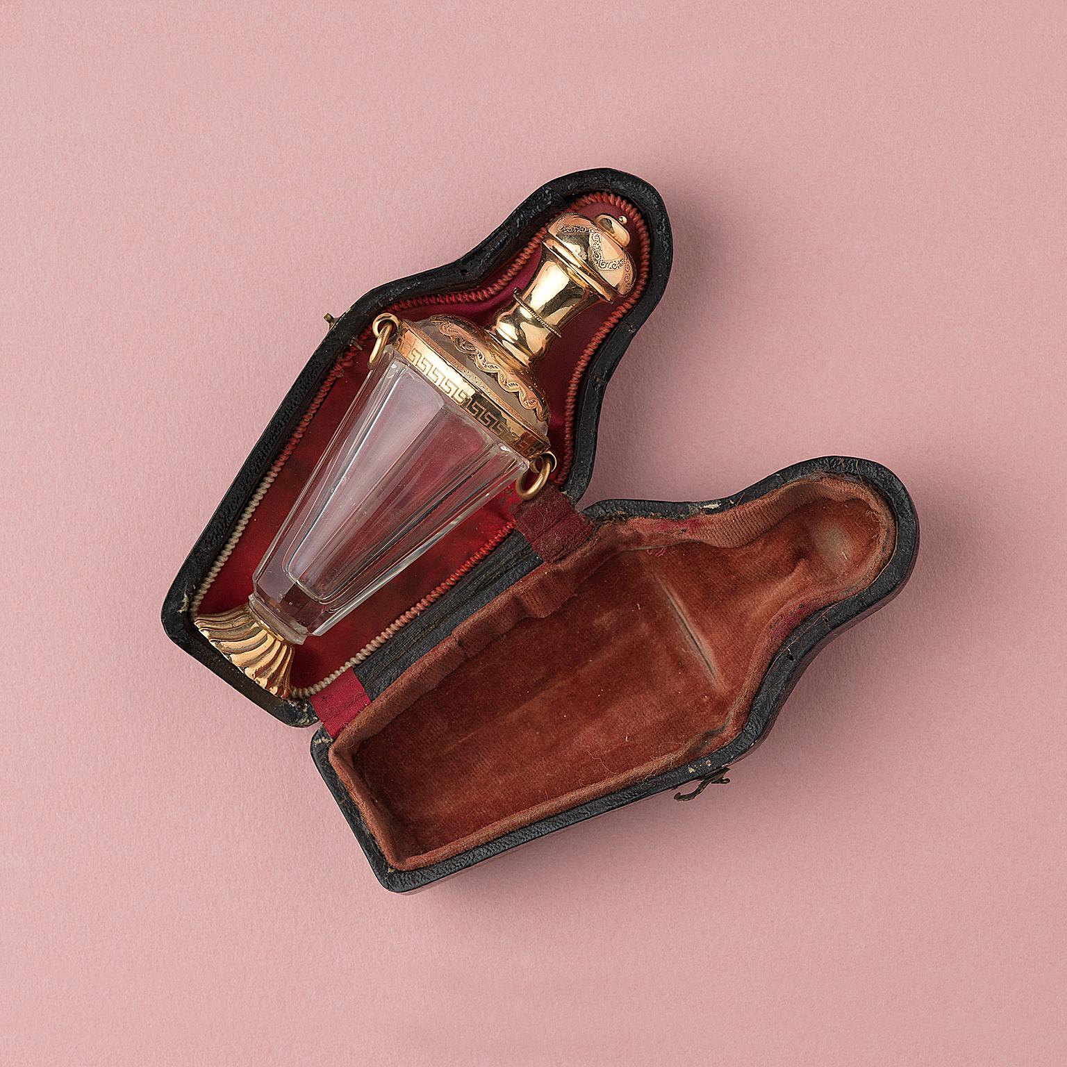 A glass scent bottle in the shape of an amphora with a 14 carat gold mounting, foot and stopper and two rings at the side in its original leather case, Netherlands, 19th century.

weight: 60.38 grams
dimensions: 11 x 4.5 cm