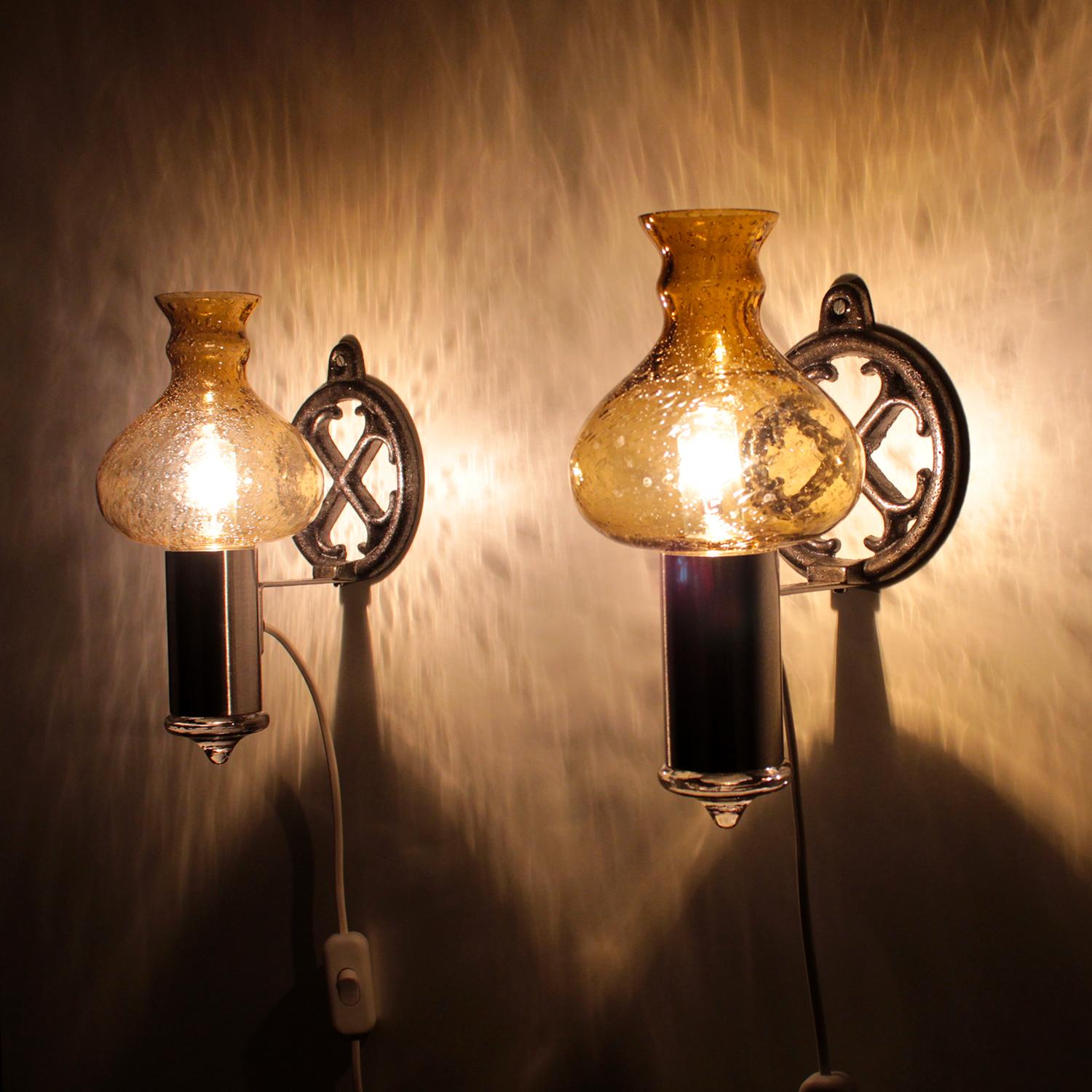 Glass Sconces (pair) - wall lamps by unknown Swedish producer in the 1970s - pair of wall lamps with crystal glass, cast iron and aluminum.

This pair of 1970s beauties features a drop shaped amber crystal glass shade, resting on an aluminum