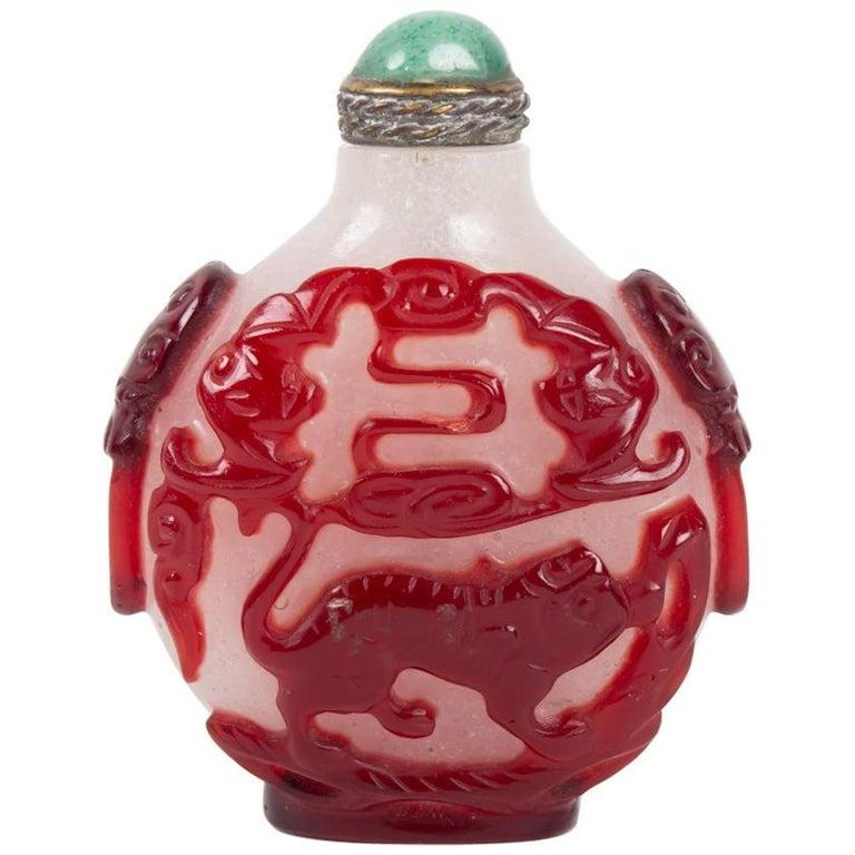 Glass snuffbox white opaque and blood red overlay with a decoration of a dragon on a face and a fantastic animal on the other, China, end of the 19th century.
Measures: H 5.5cm, W 4.5cm, P 2.5cm.