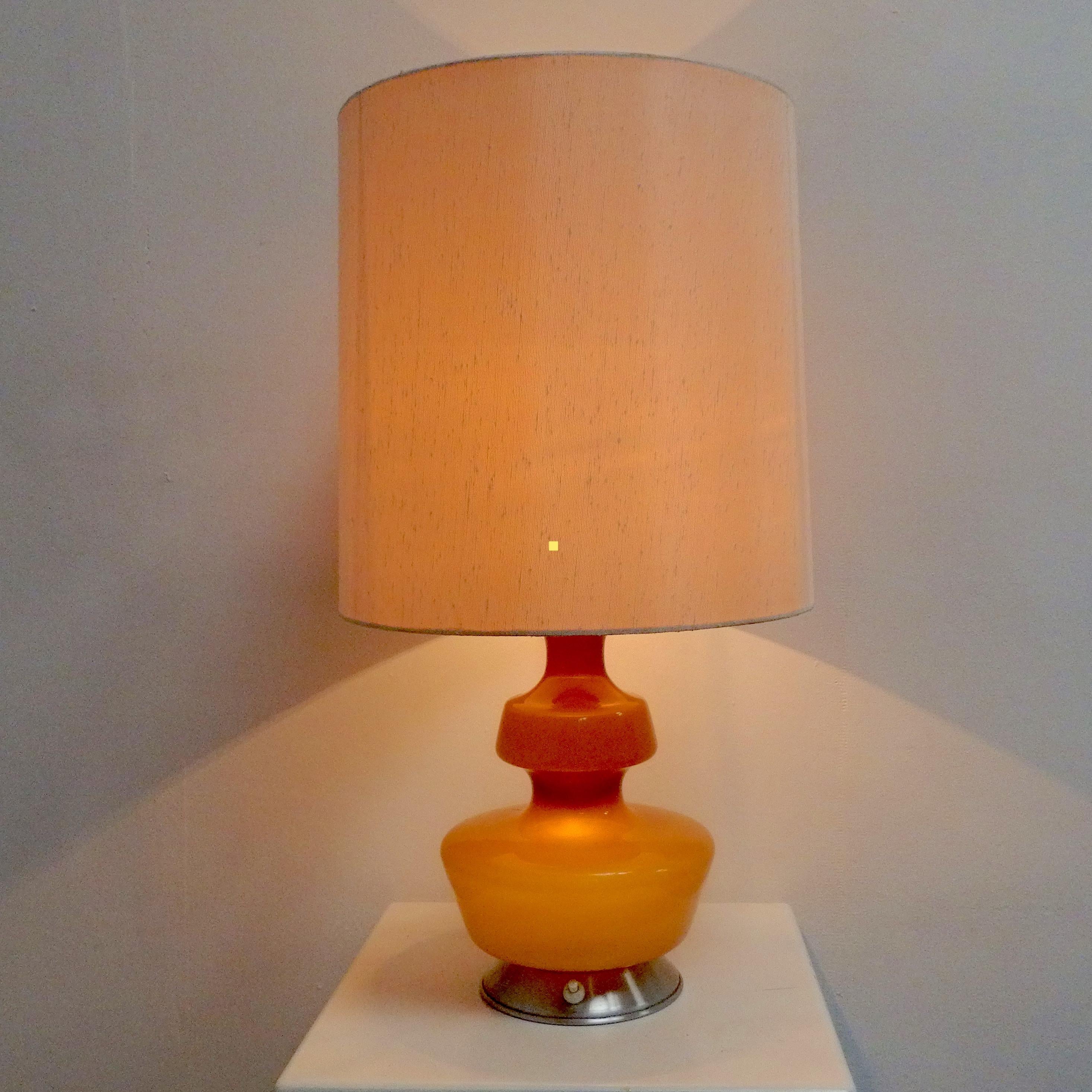 Glass table lamp made by Holmegaard Belgium. Inside of the glass base there is also a lightbulb and can lighted separate. the shade is made of silk. A beautiful warm ochreous glass table lamp made by Holmegaard Belgium in de 1960's.  from the Rupel