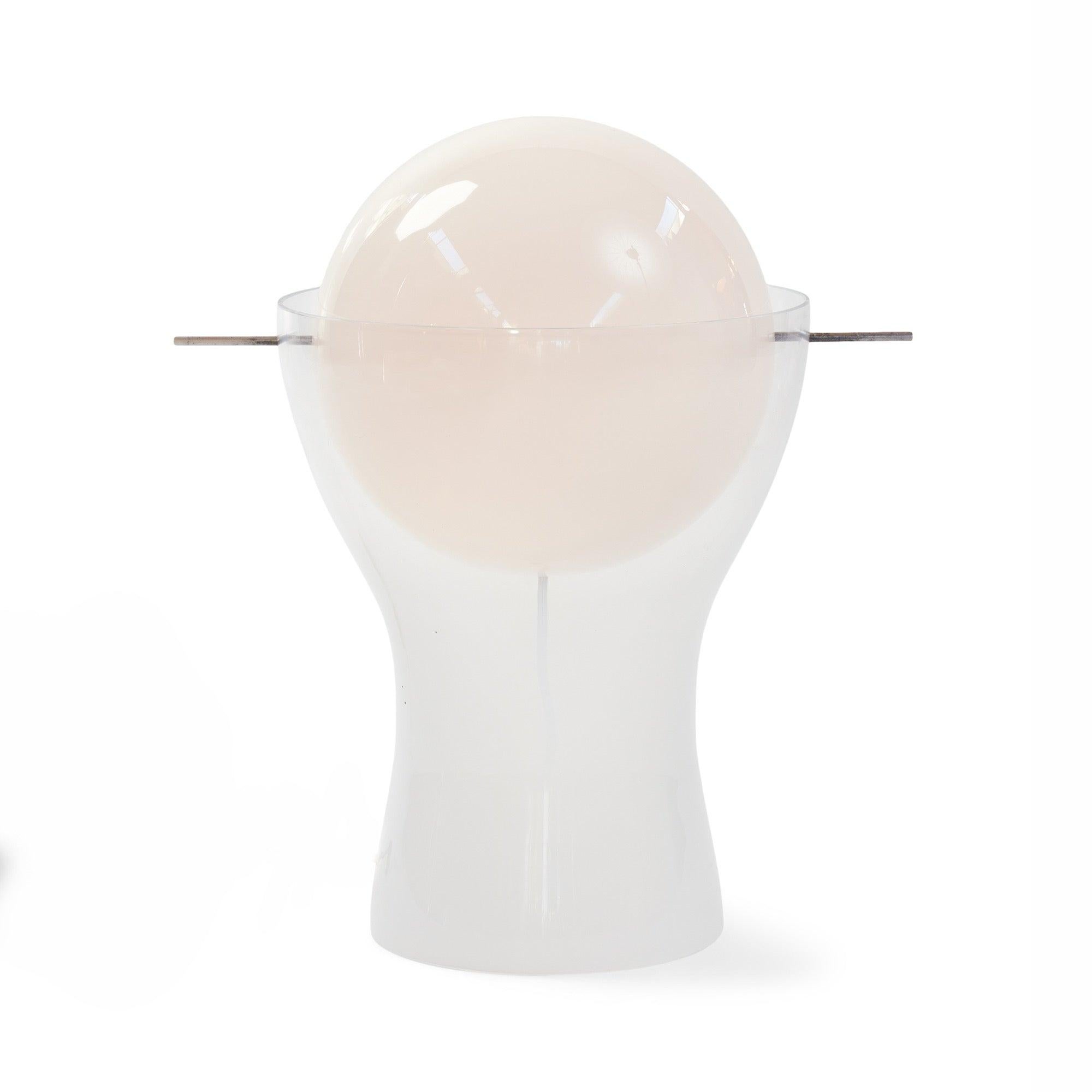 A milk glass illuminated globe suspended by a metal rod in a glass vessel.