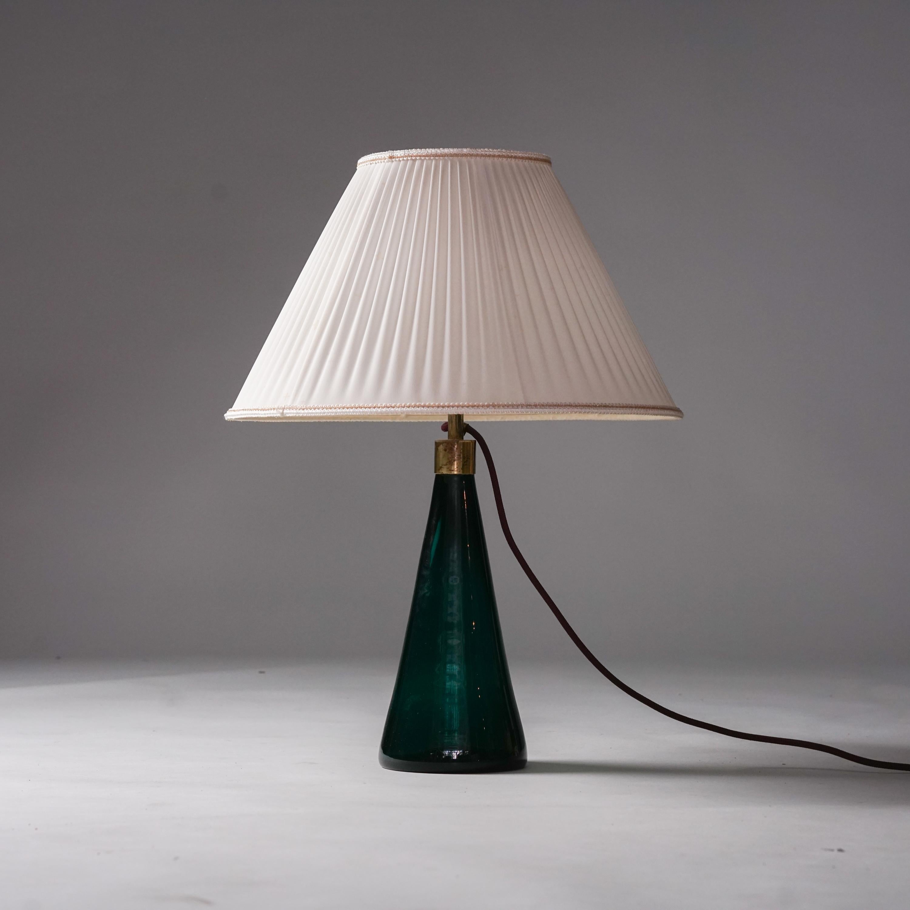 Lámpara de mesa de cristal, diseñada por Gunnel Nyman, fabricada por Idman Oy, años 1940/1950. Pantalla original de seda y detalles de latón. Marco de cristal verde turquesa. Buen estado vintage, pátina menor acorde con la edad y el uso. 

Gunnel