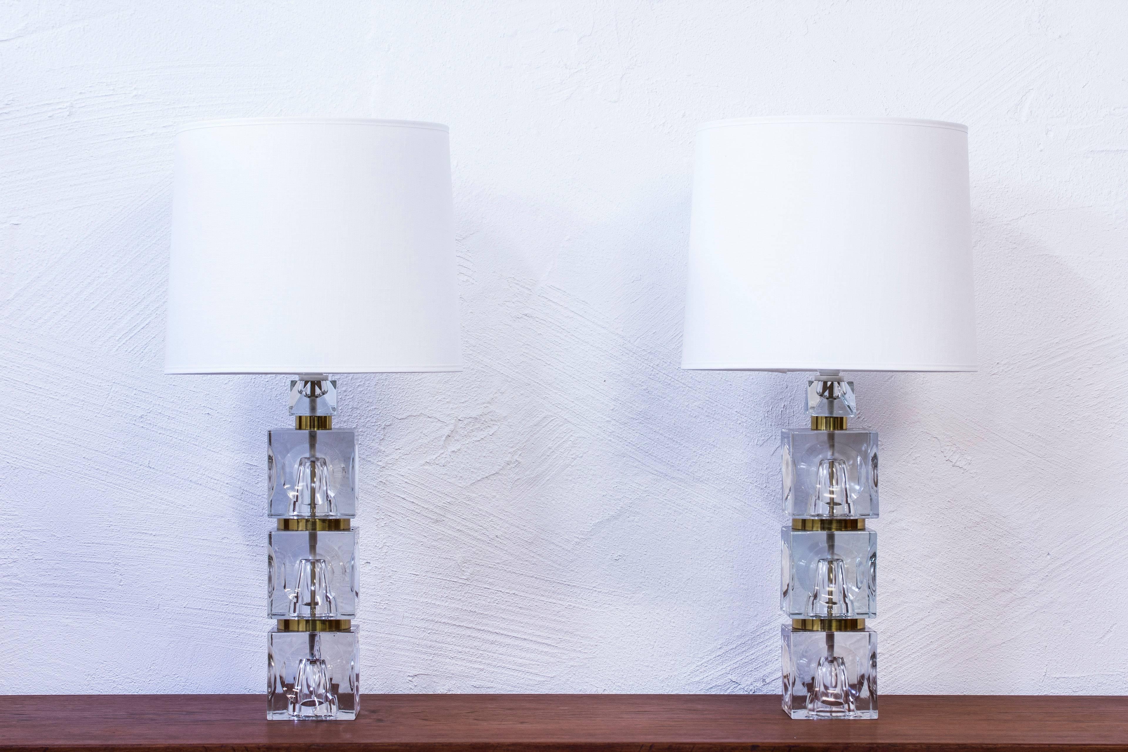 Table lamps made from handblown clear glass with brass details. Attributed to Swedish glass artist Sven Palmqvist and Orrefors. Made in Sweden during the 1960s. New lampshades in white cotton. New electric cables. Light switch on the light fixture