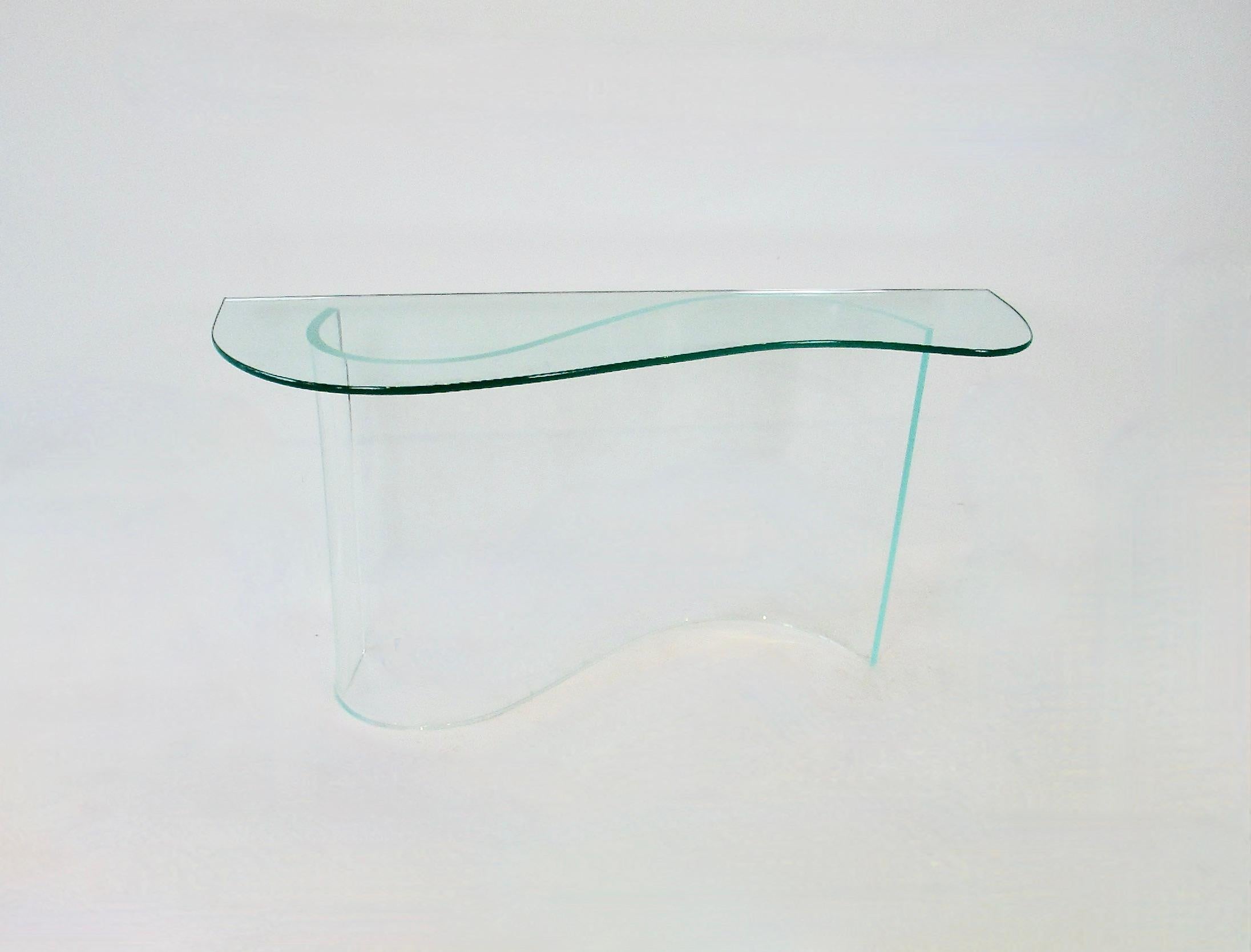 Merveilleuse par sa simplicité, la table console entry way . Le plateau en verre bio-morphique flotte sur une base ondulée en lucite. Très bon état général. Le verre mesure 52 de large et 16 de profondeur d'un côté et s'abaisse à 12 de profondeur de