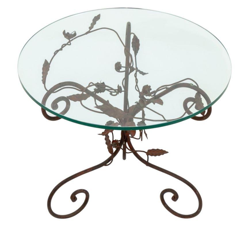 Table d'appoint en fer forgé peint en rouge à motif de feuillage, plateau circulaire en verre au-dessus de trois supports à la forme chantournée. 17.5
