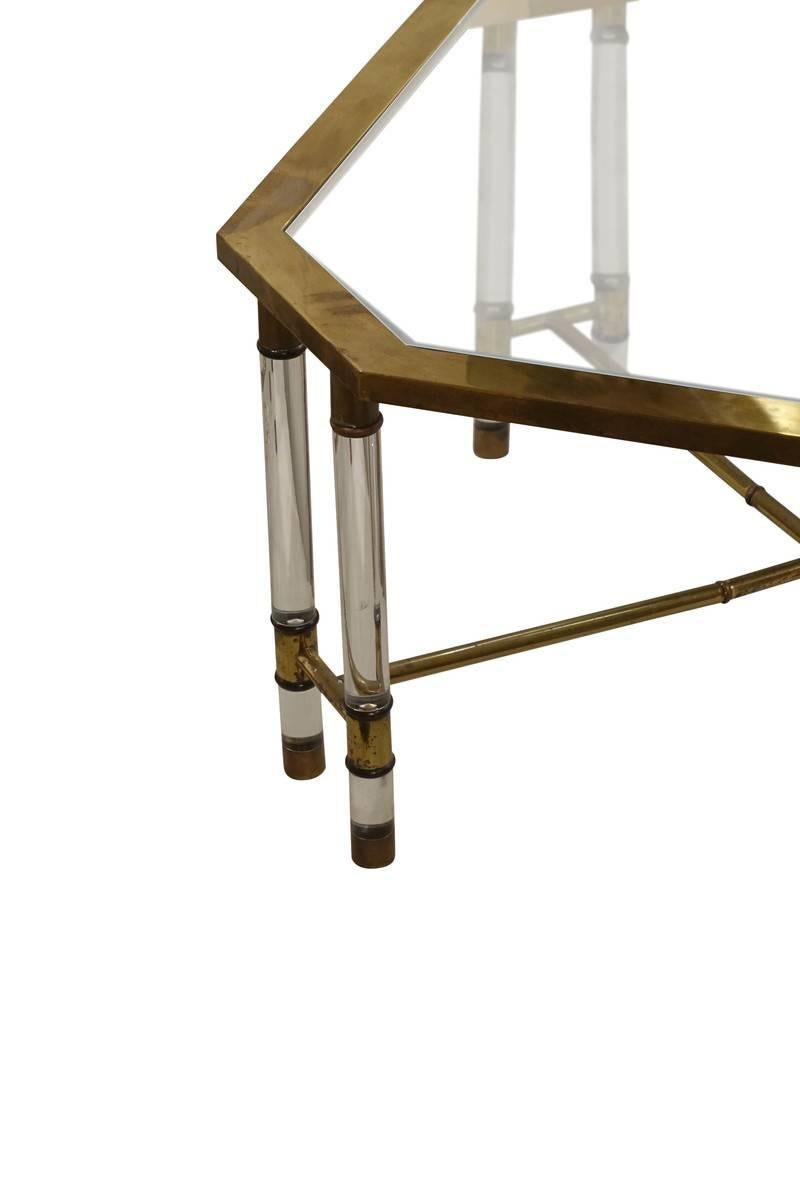 1960s Belgian coffee table.
Pairs of rounded Lucite legs on each of four angled corners.
Glass top.
Brass trim.
Brass bamboo motif stretcher.
 