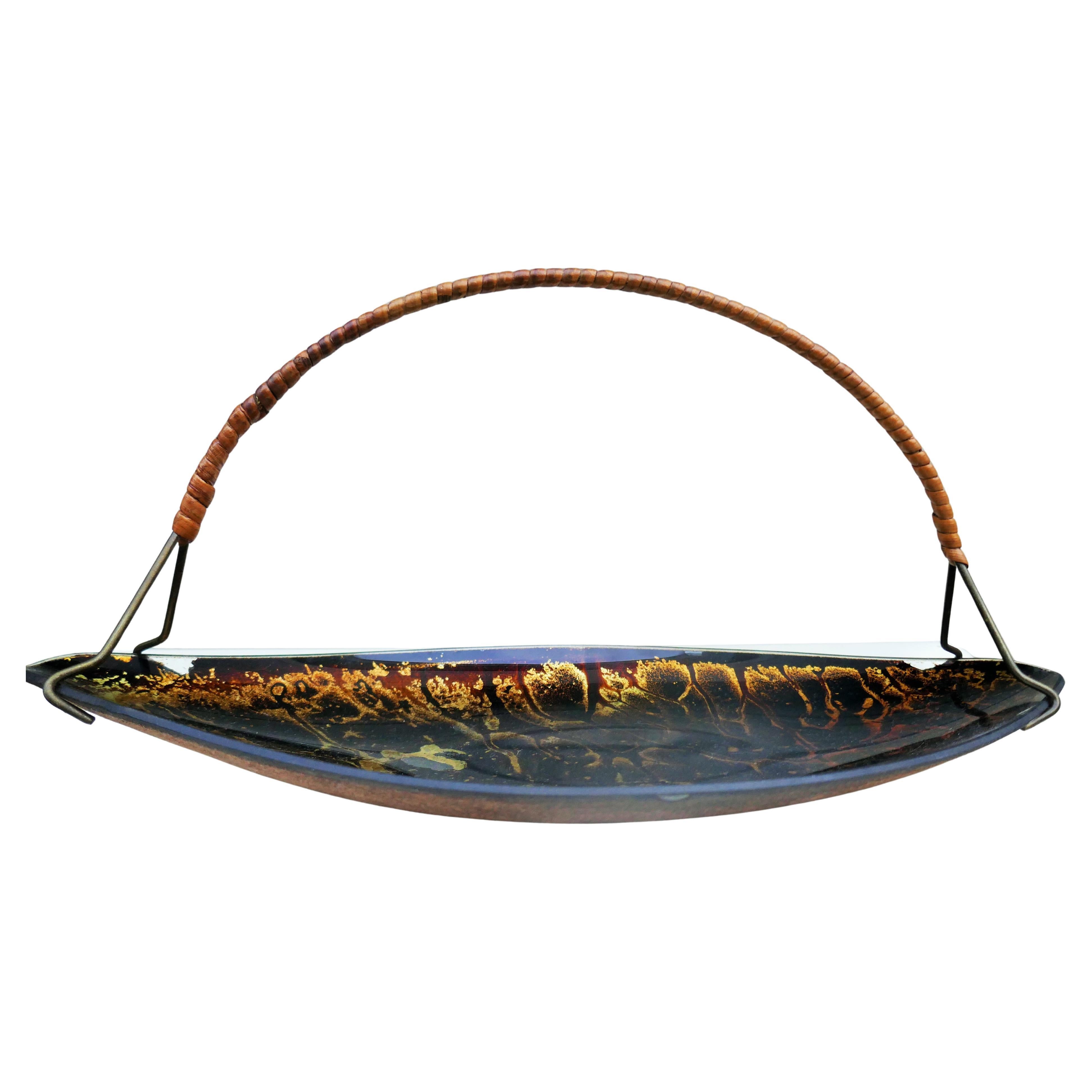 Glass tray with possible gold leaf and an abstract design, secured to the base with a fabric-like finish.
There are some missing parts where the handle supports the glass.
Overall, in good condition.
Thank you.