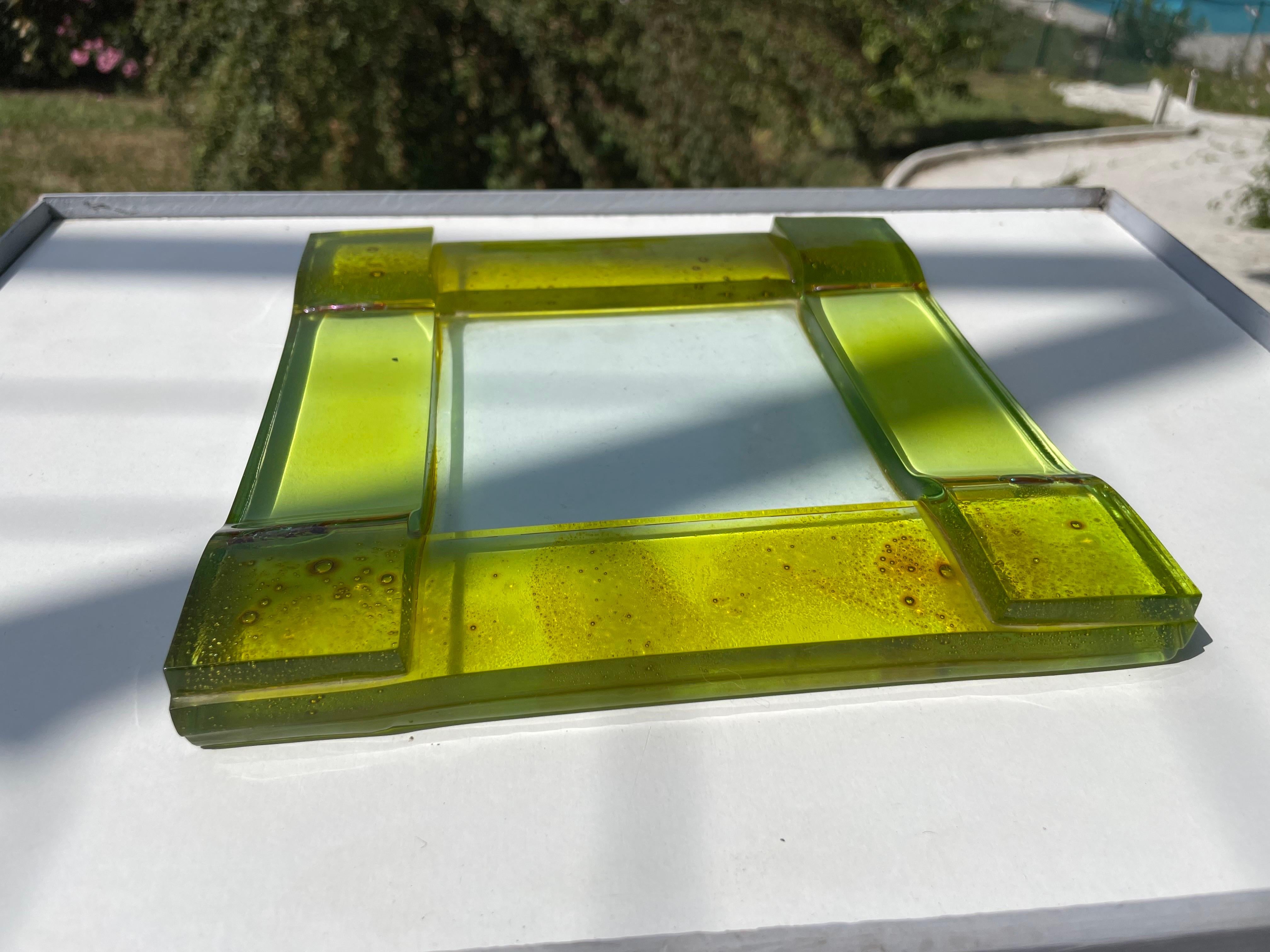 This glass trivet was produced by Poliarte in Italy in the 1960s. You can see that it is glass made by an artist, it is irregular, it is thick and it is heavy. Its color is green and you can see a patina related to its use.