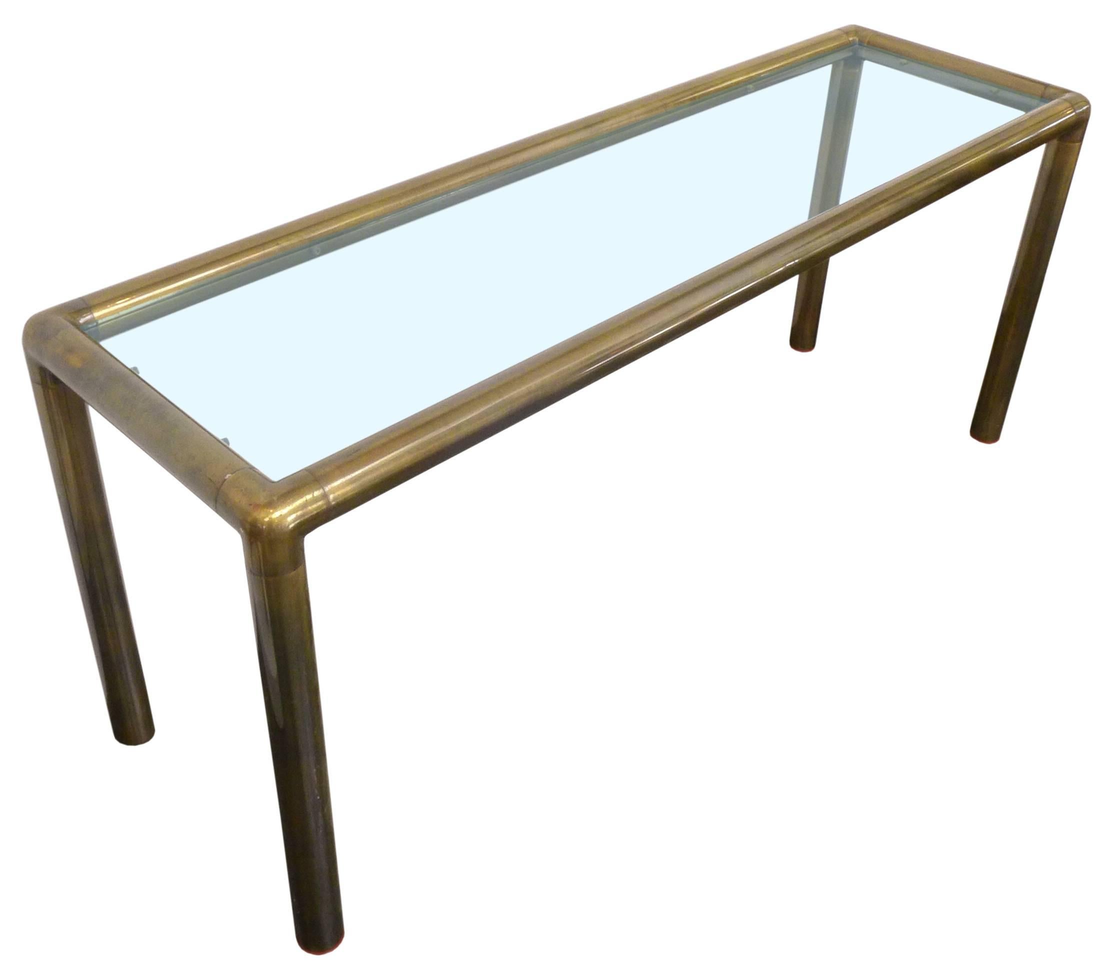 A wonderful glass and tubular brass console or sofa table. A simple, elegant frame of thick-gauge tubular brass cradling an inset glass top. Wonderful scale and mix of materials, an even patina to the brass throughout. In the manner of and possibly